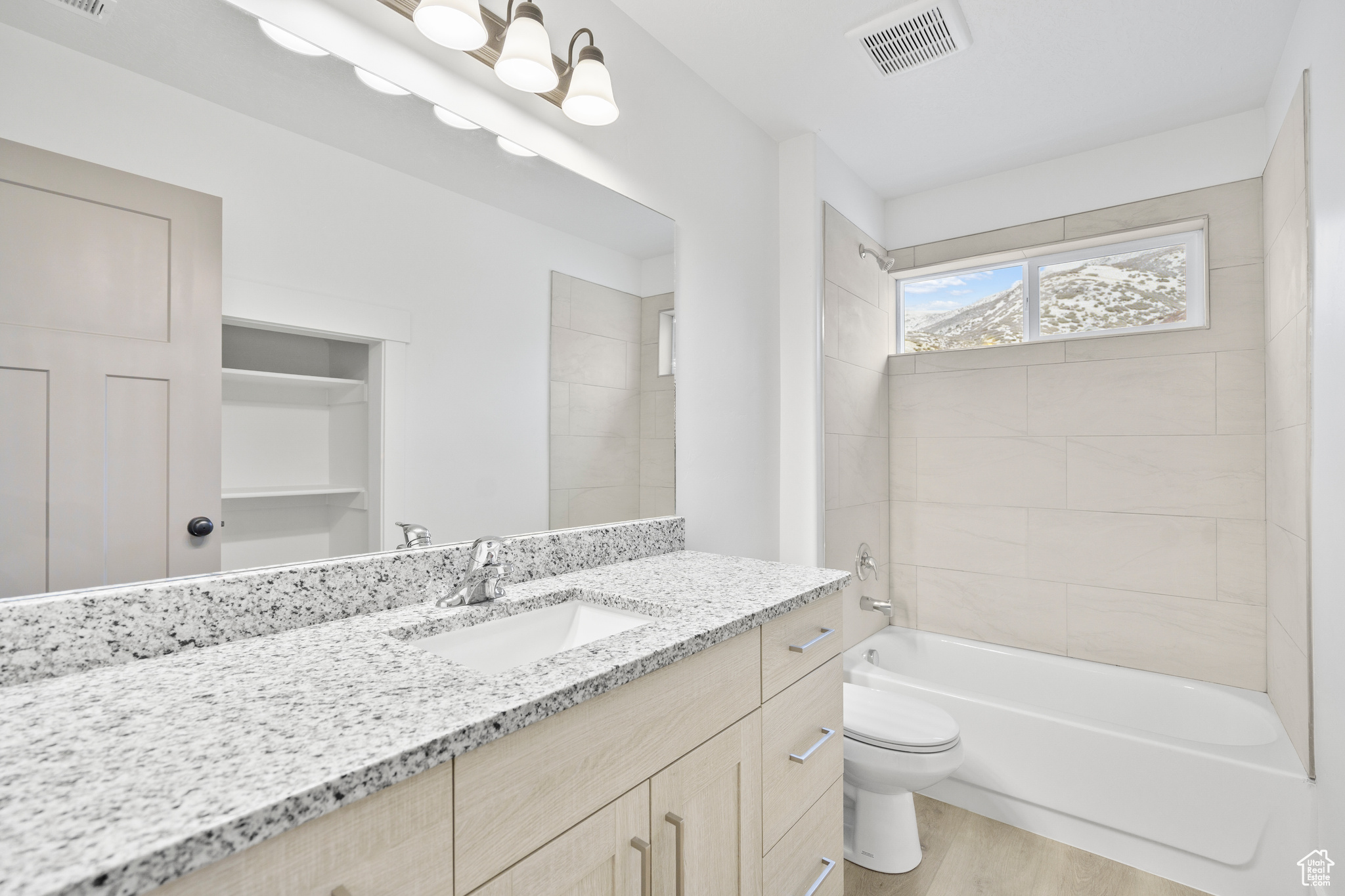 Full bathroom featuring hardwood / wood-style floors, vanity, toilet, and tiled shower / bath