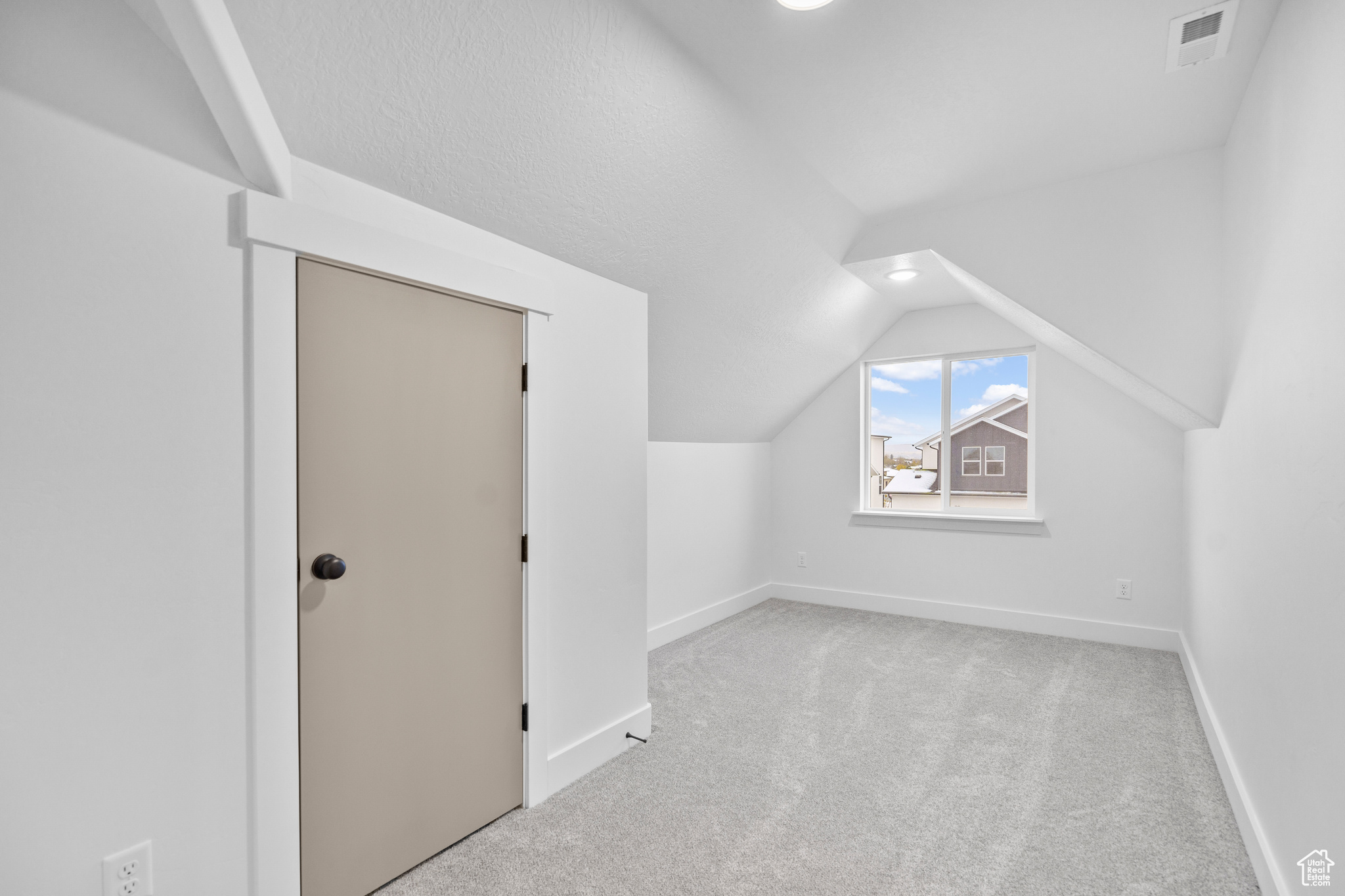 Additional living space with light colored carpet and vaulted ceiling