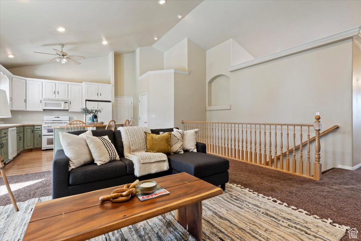 Living room featuring ceiling fan, light wood-type flooring, and high vaulted ceiling