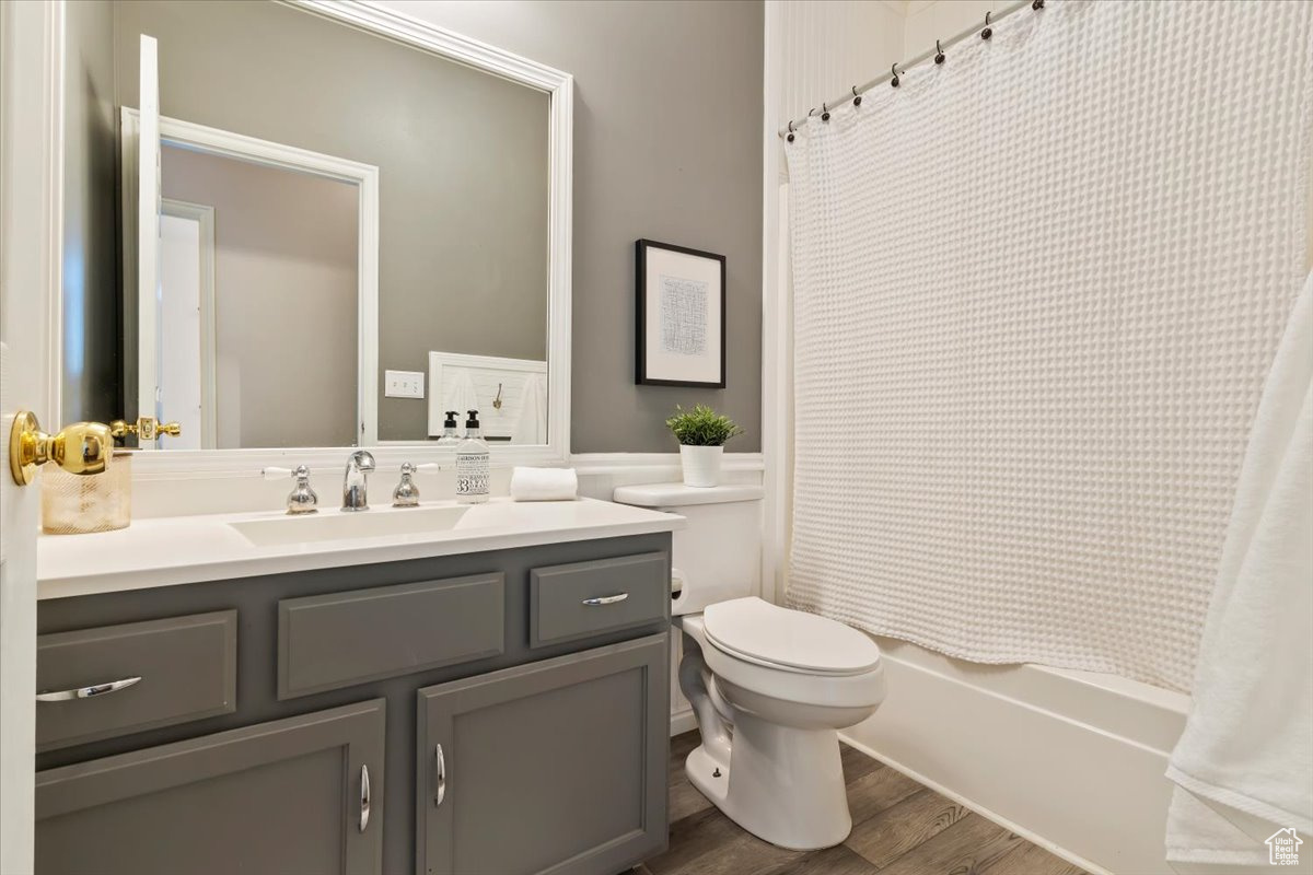 Full bathroom with vanity, toilet, wood-type flooring, and shower / tub combo