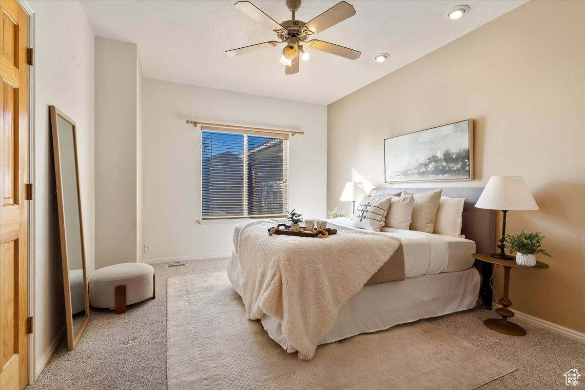 Bedroom with ceiling fan and light colored carpet