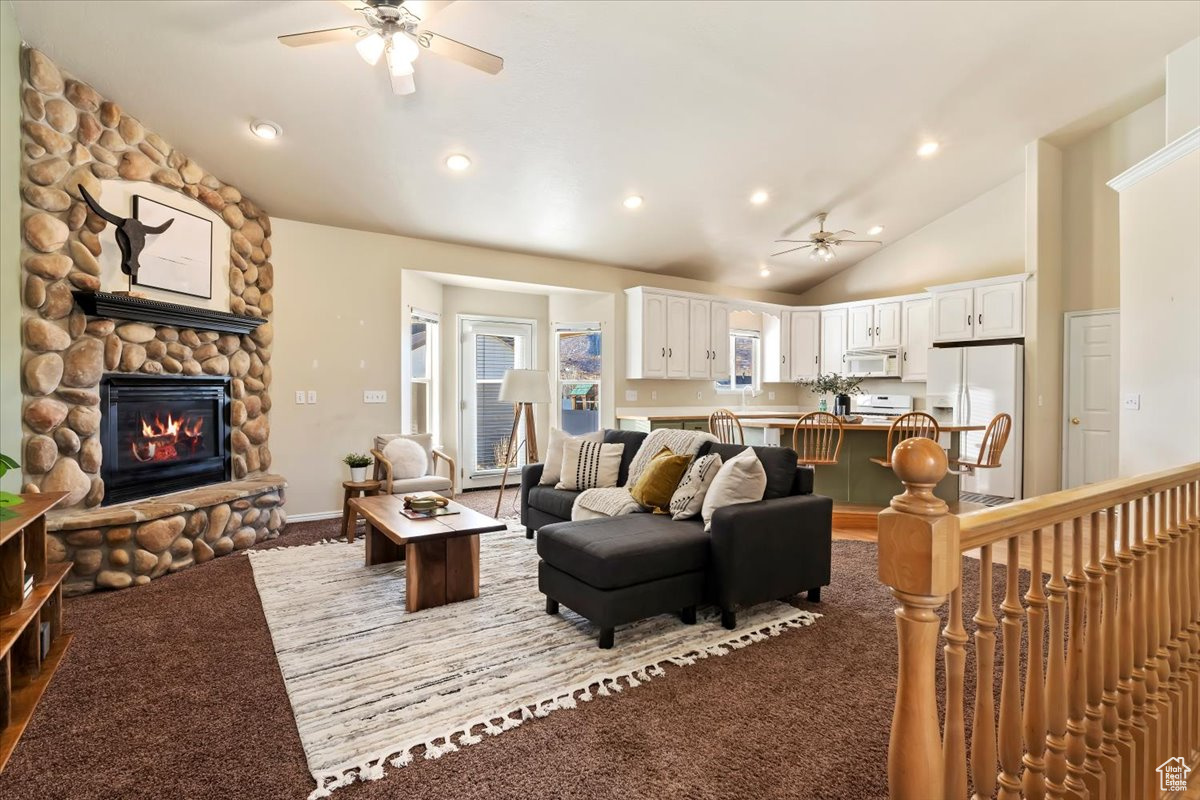 Living room with ceiling fan, a fireplace, carpet, and high vaulted ceiling