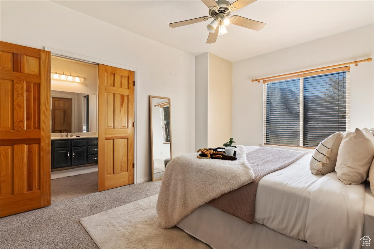 Bedroom with sink, ceiling fan, light colored carpet, and ensuite bathroom