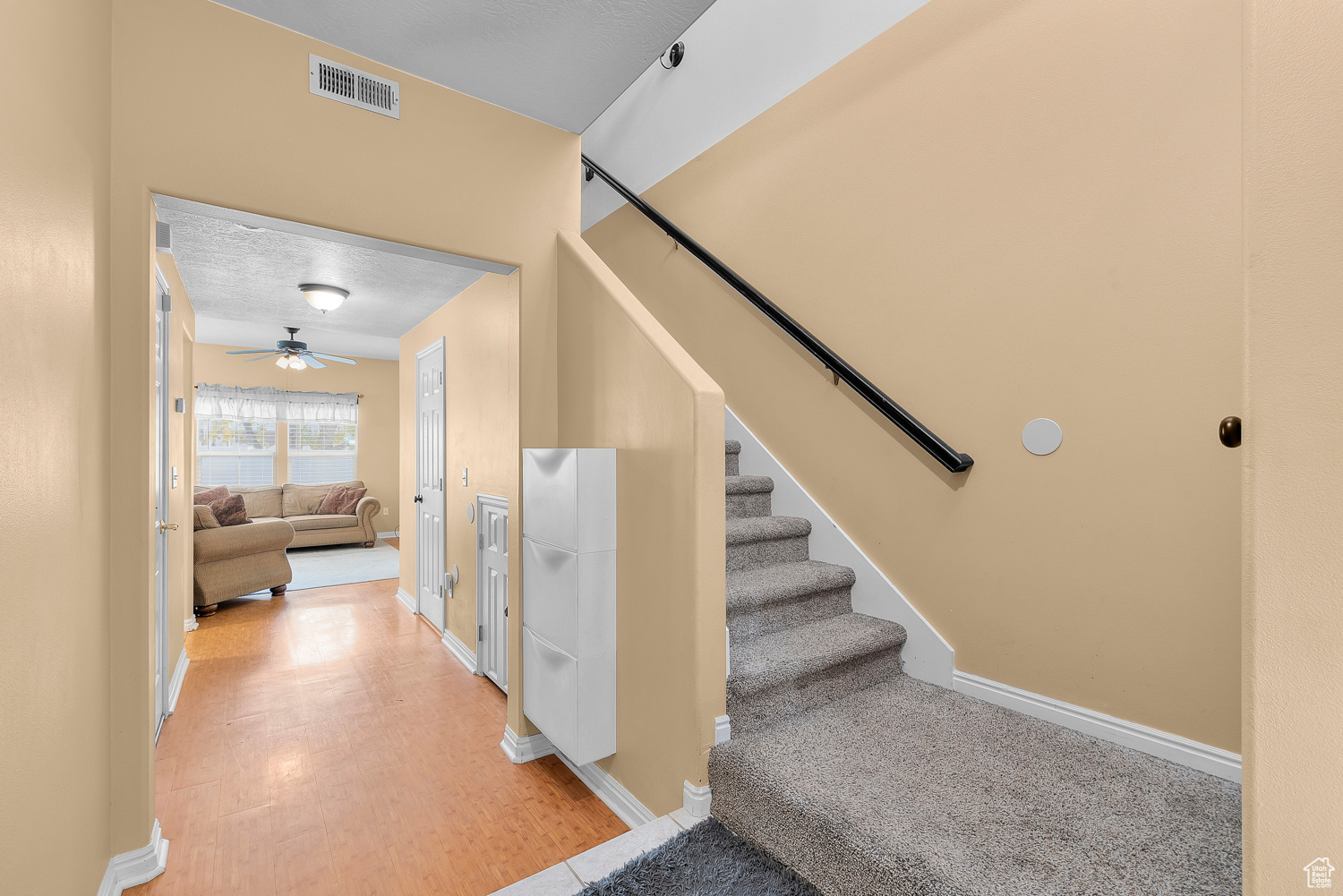 Staircase featuring wood-type flooring, a textured ceiling, and ceiling fan