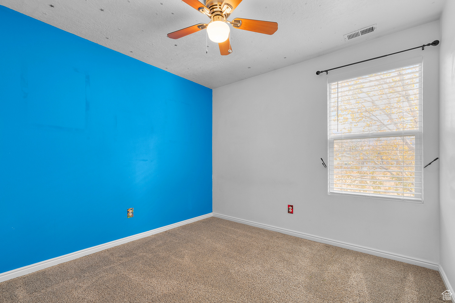 Carpeted spare room featuring ceiling fan and a textured ceiling