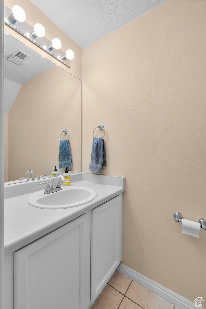 Bathroom with tile patterned floors, vanity, and a textured ceiling