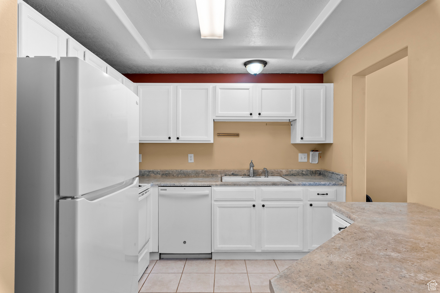 Kitchen with white cabinetry, white appliances, sink, and light tile patterned floors