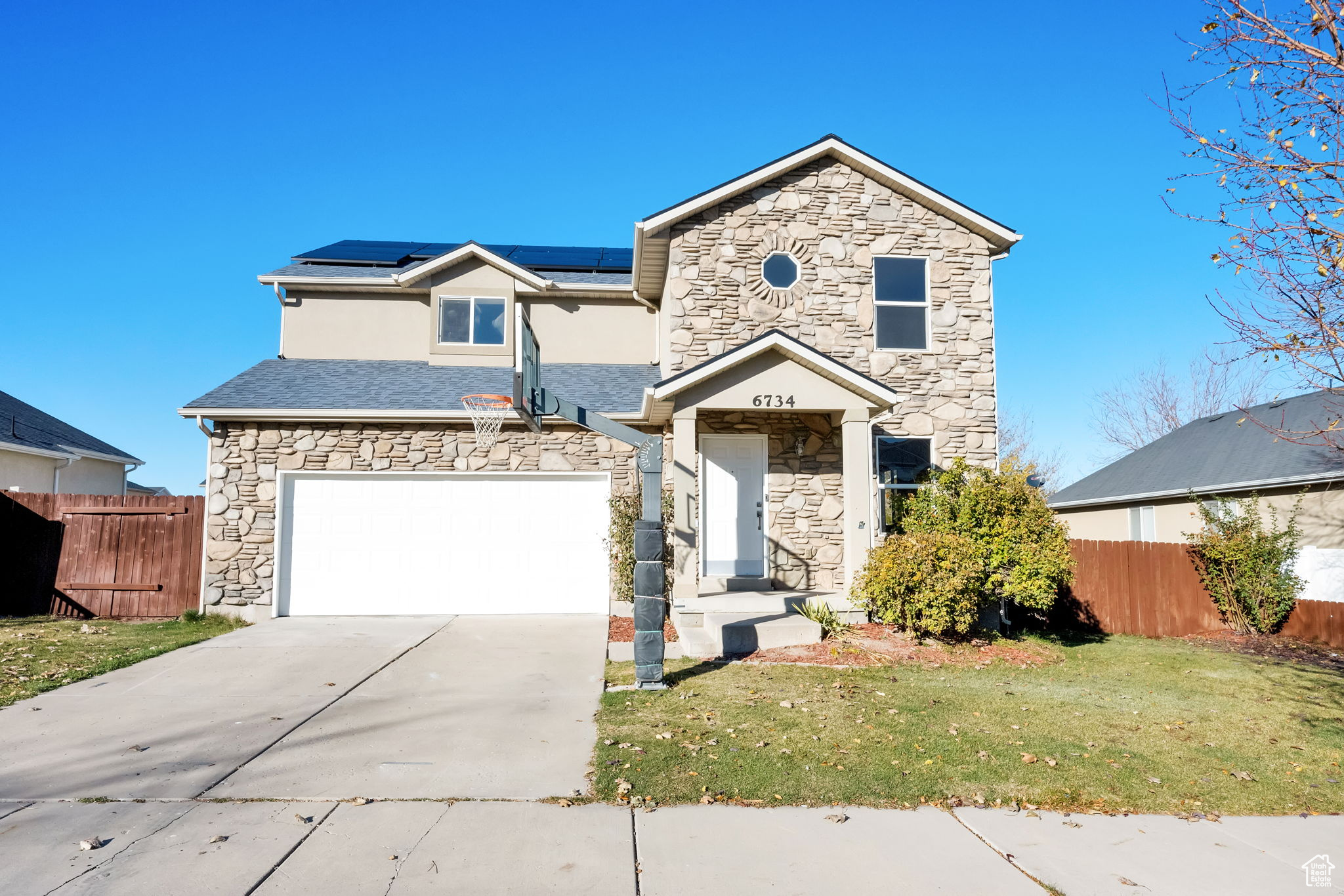 Front facade with solar panels, a garage, and a front lawn