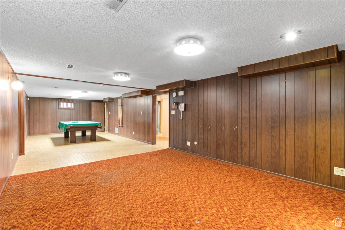 Rec room with wooden walls, a textured ceiling, and pool table