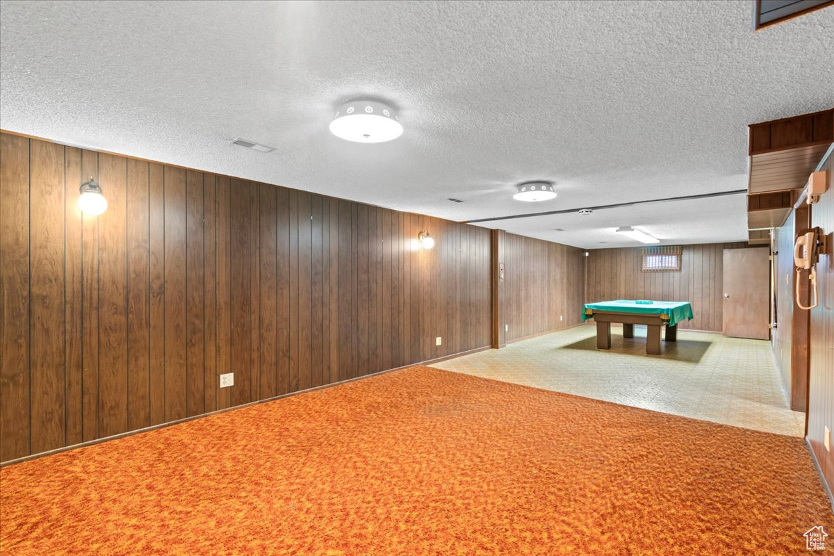 Playroom featuring carpet flooring, billiards, a textured ceiling, and wooden walls