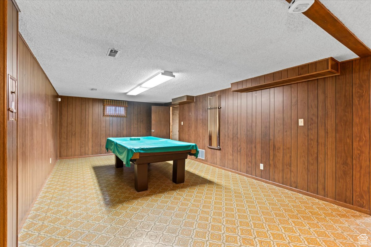 Game room featuring wooden walls, a textured ceiling, and billiards