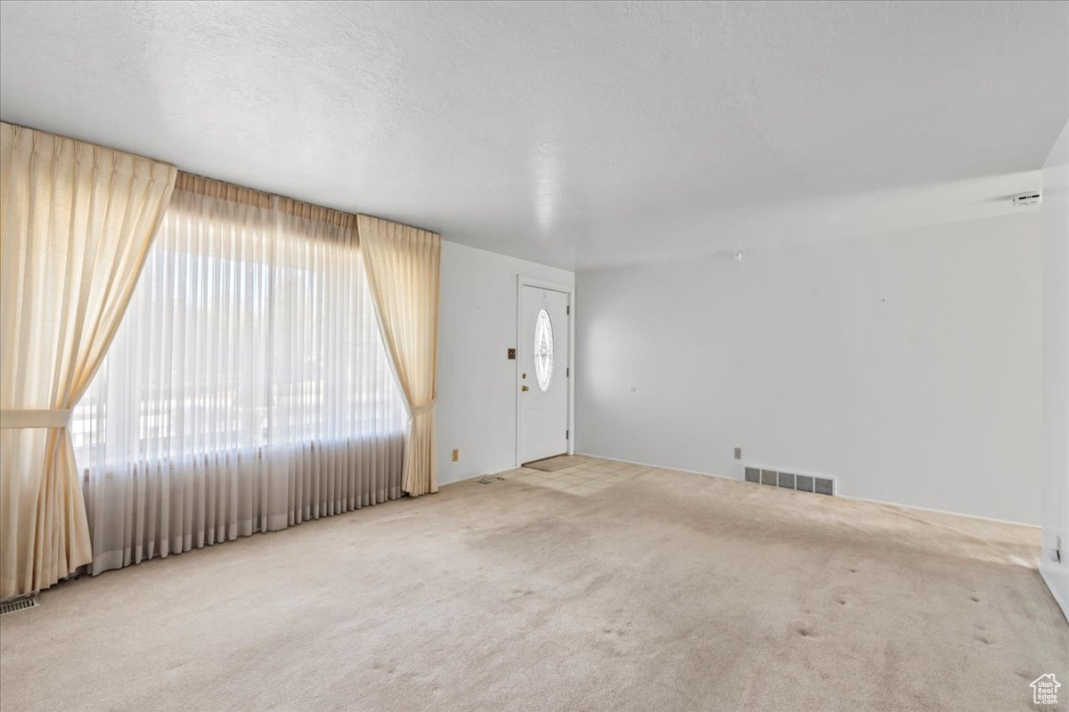 Entrance foyer with a textured ceiling and light colored carpet