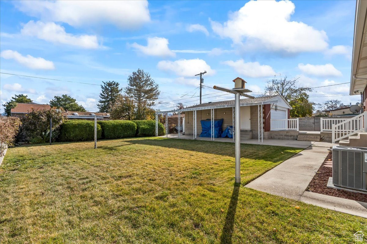 View of yard with a garage, cooling unit, and a patio area