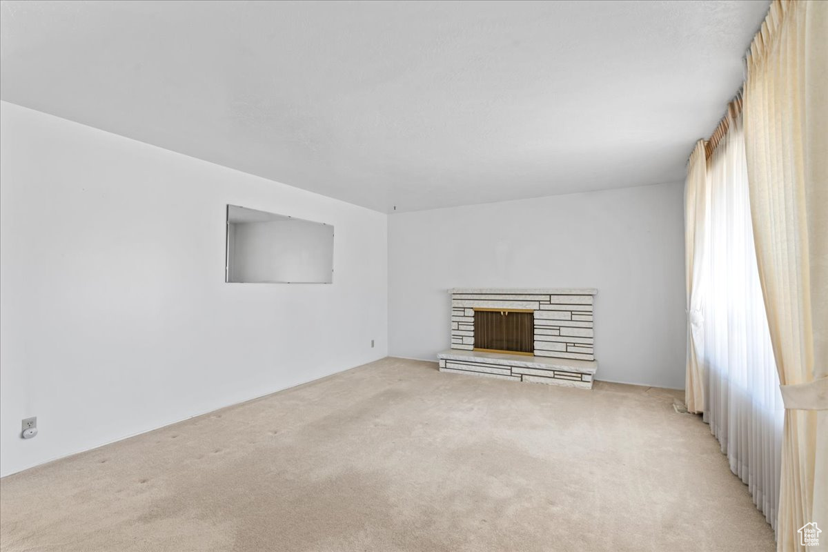 Unfurnished living room featuring light carpet and a fireplace