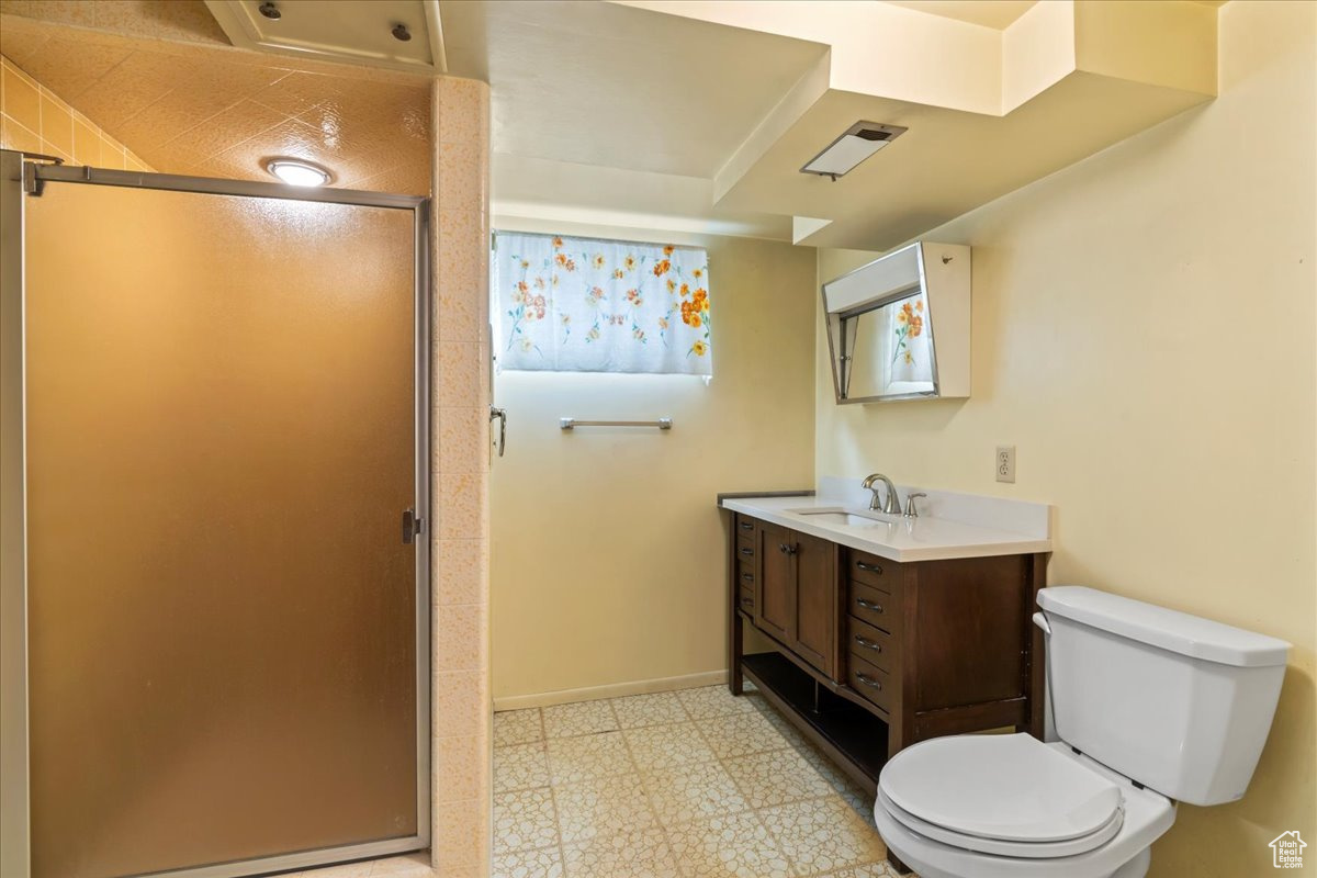 Bathroom featuring toilet, vanity, and walk in shower