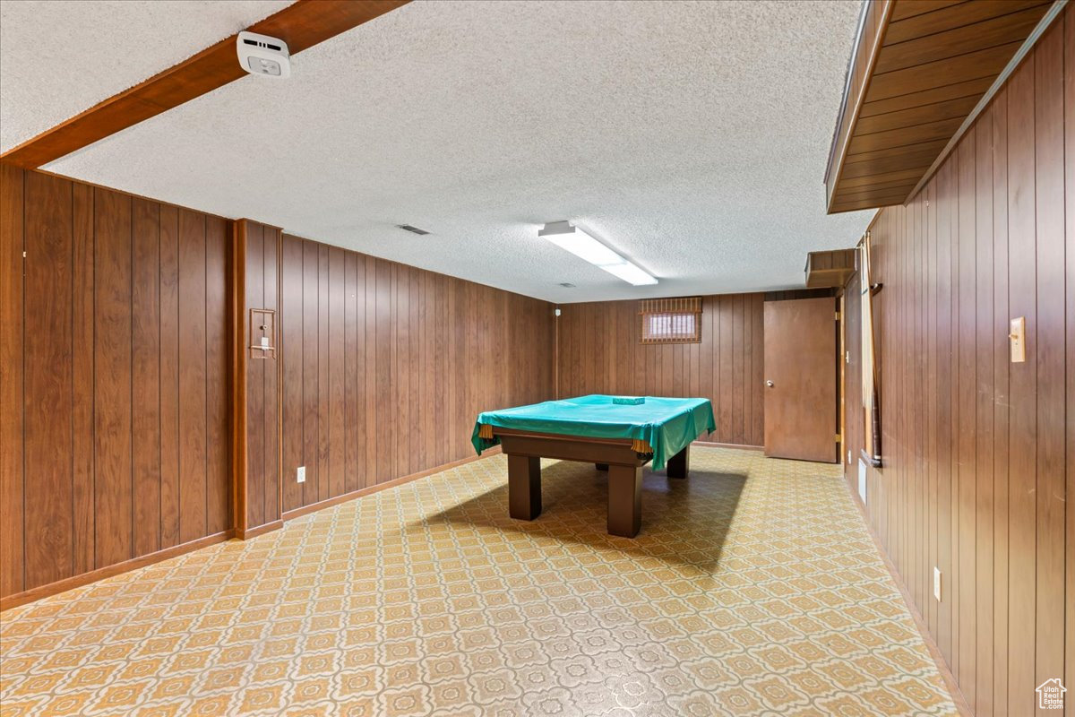 Playroom with a textured ceiling, billiards, and wood walls