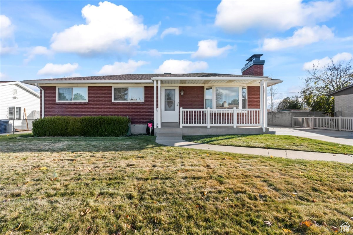 View of front of home with central air condition unit, a porch, and a front yard