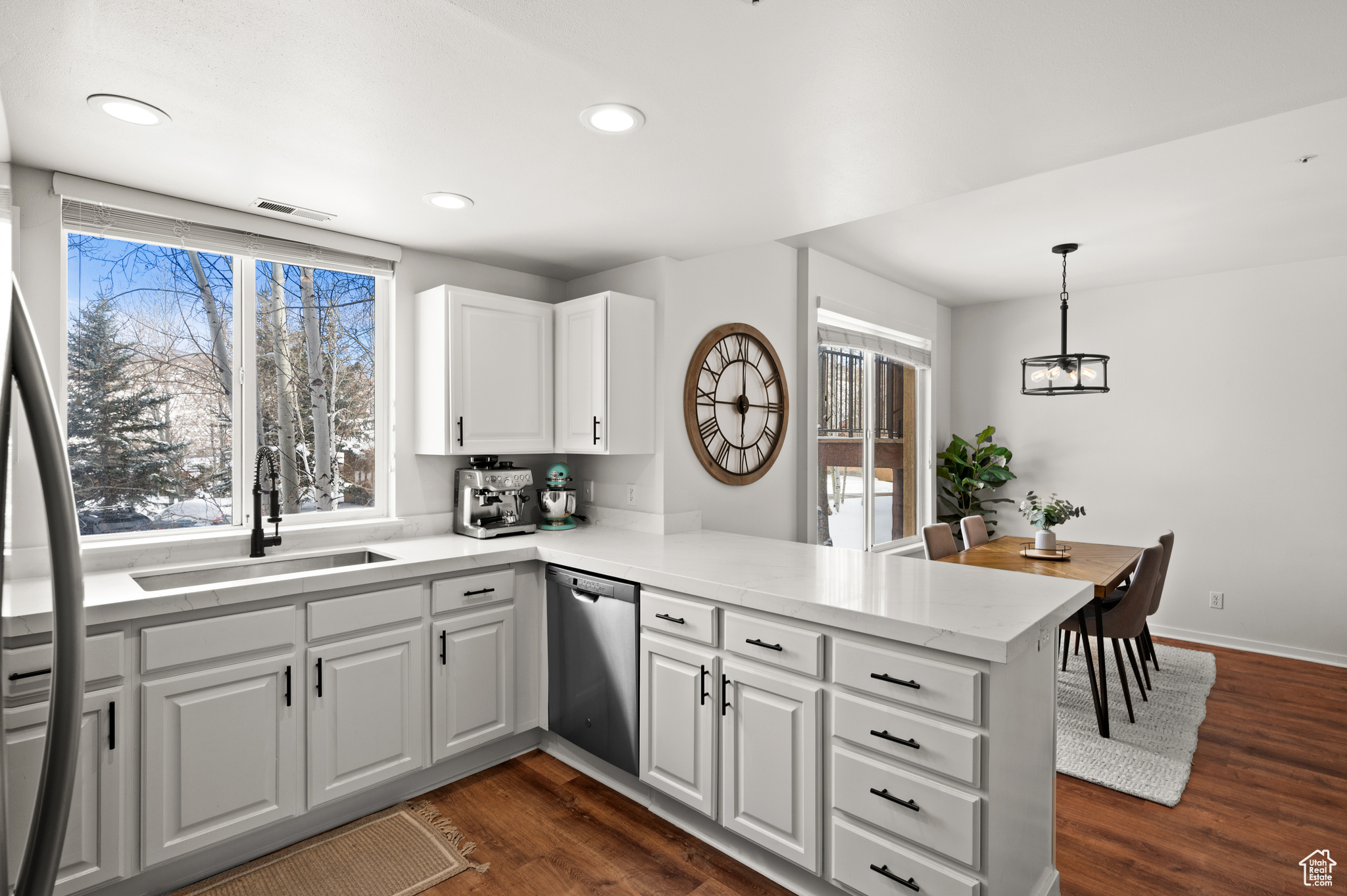 Kitchen with dishwasher, white cabinetry, kitchen peninsula, and dark hardwood / wood-style floors