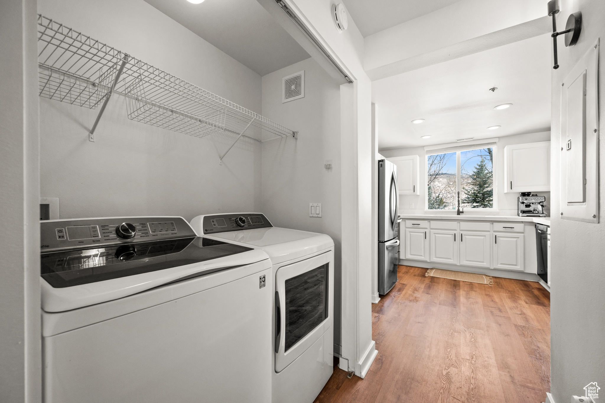 Laundry area with light wood-type flooring, a barn door, and separate washer and dryer