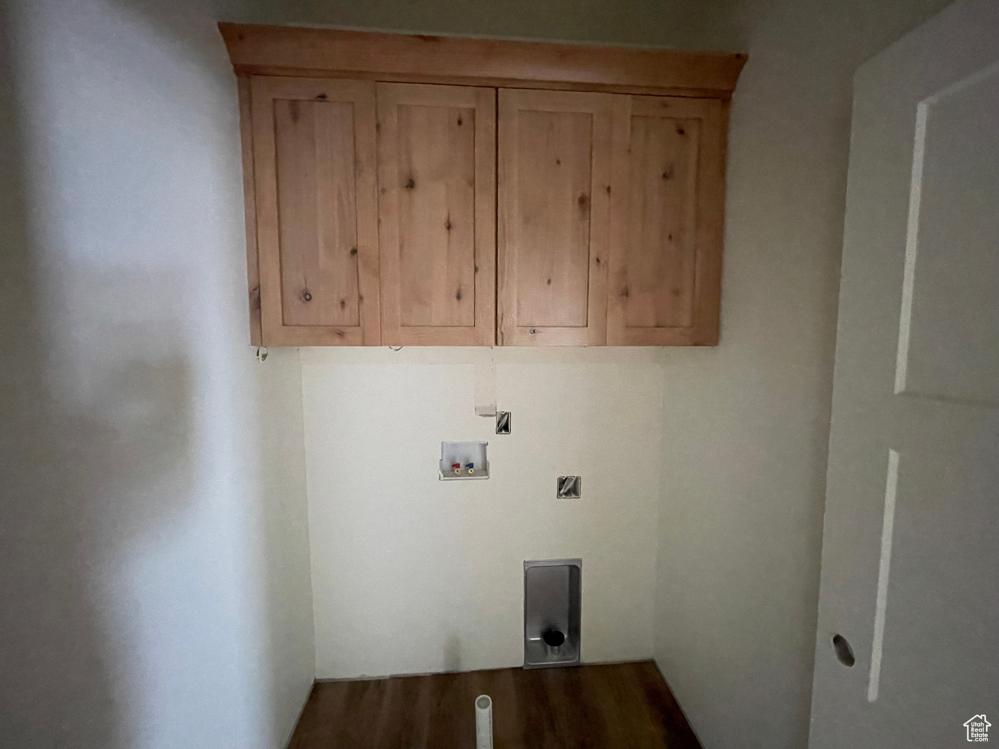 Clothes washing area featuring hookup for an electric dryer, cabinets, hardwood / wood-style flooring, and washer hookup