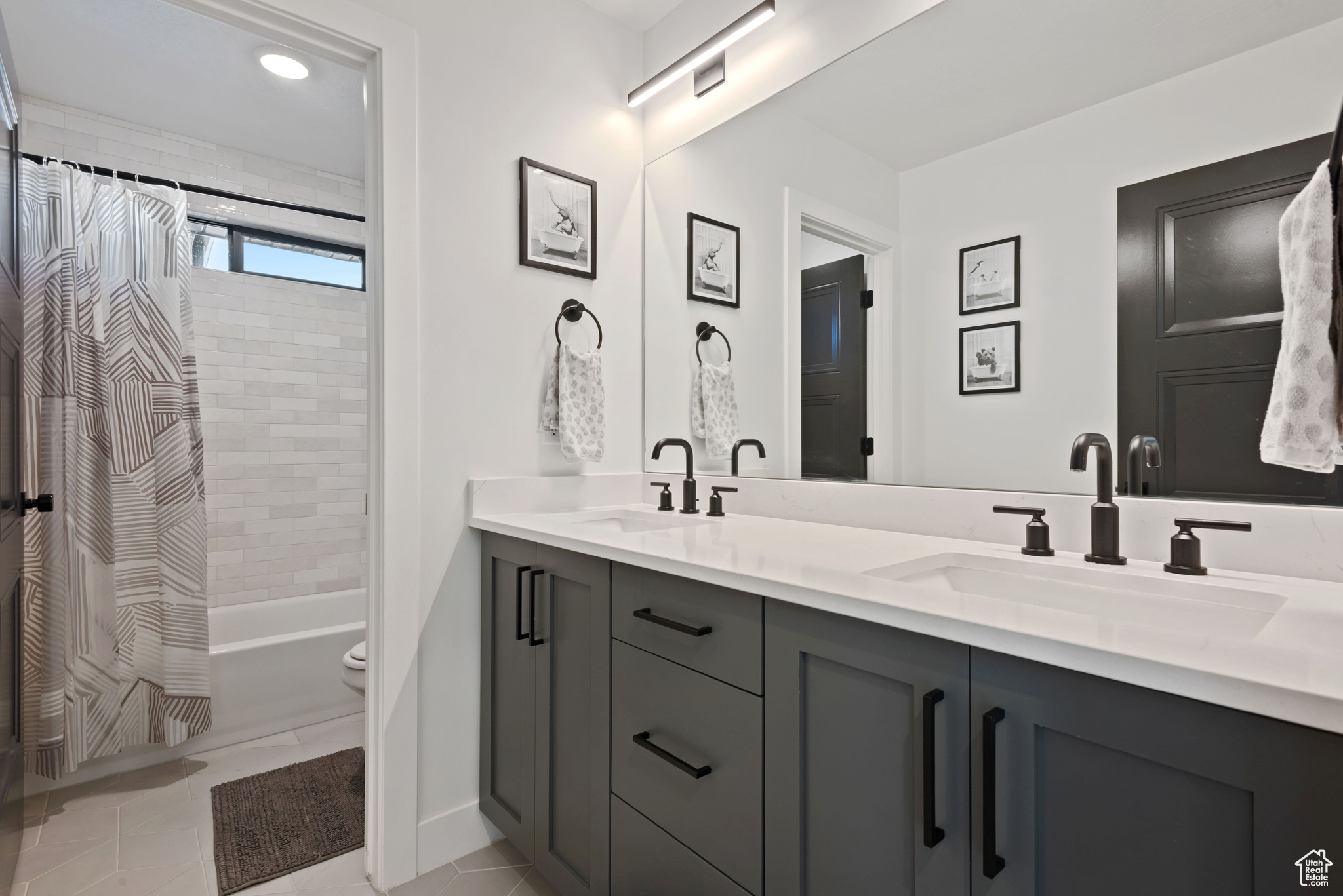 Full bathroom with tile patterned flooring, vanity, toilet, and shower / bath combo with shower curtain