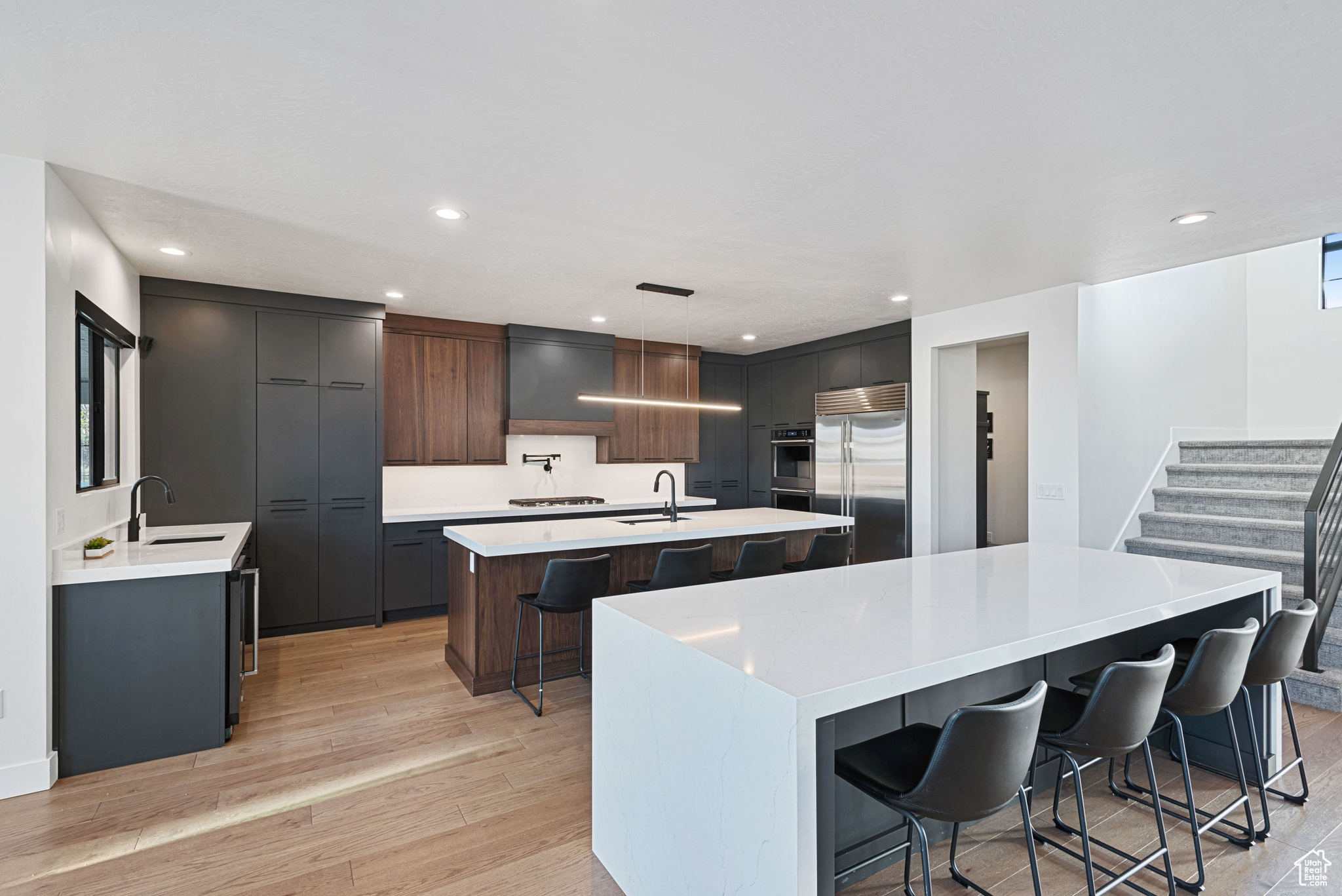 Kitchen with a kitchen breakfast bar, a spacious island, decorative light fixtures, light hardwood / wood-style floors, and stainless steel built in fridge