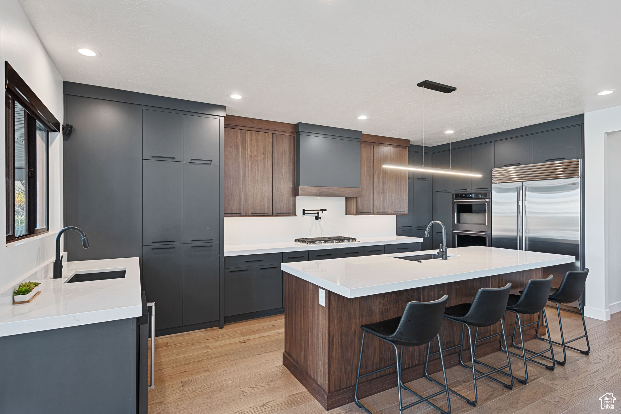 Kitchen featuring sink, light hardwood / wood-style floors, decorative light fixtures, and appliances with stainless steel finishes