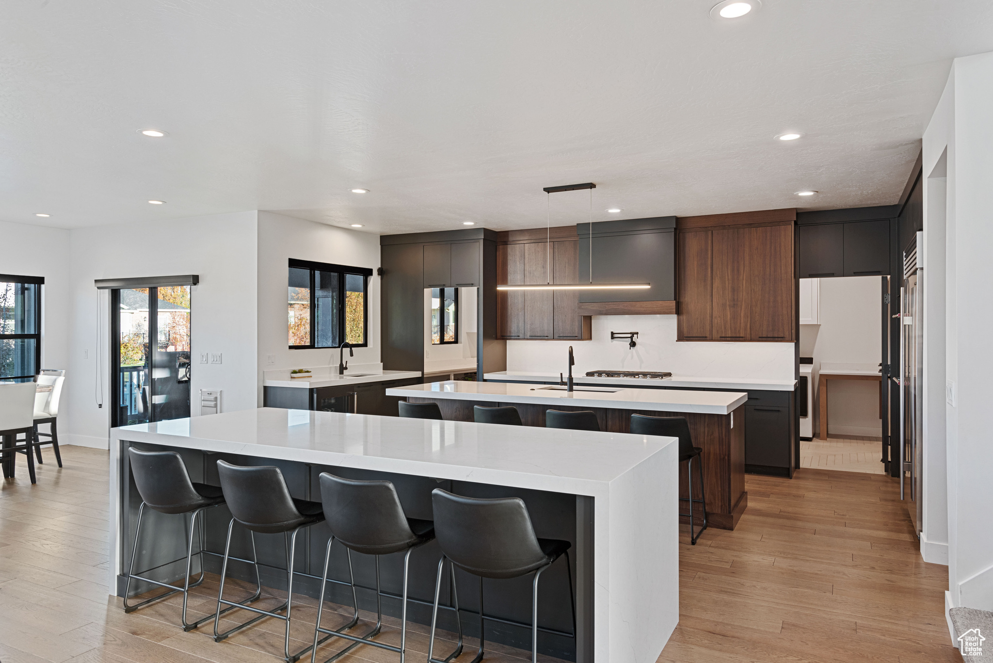 Kitchen featuring sink, hanging light fixtures, light hardwood / wood-style flooring, an island with sink, and a kitchen bar