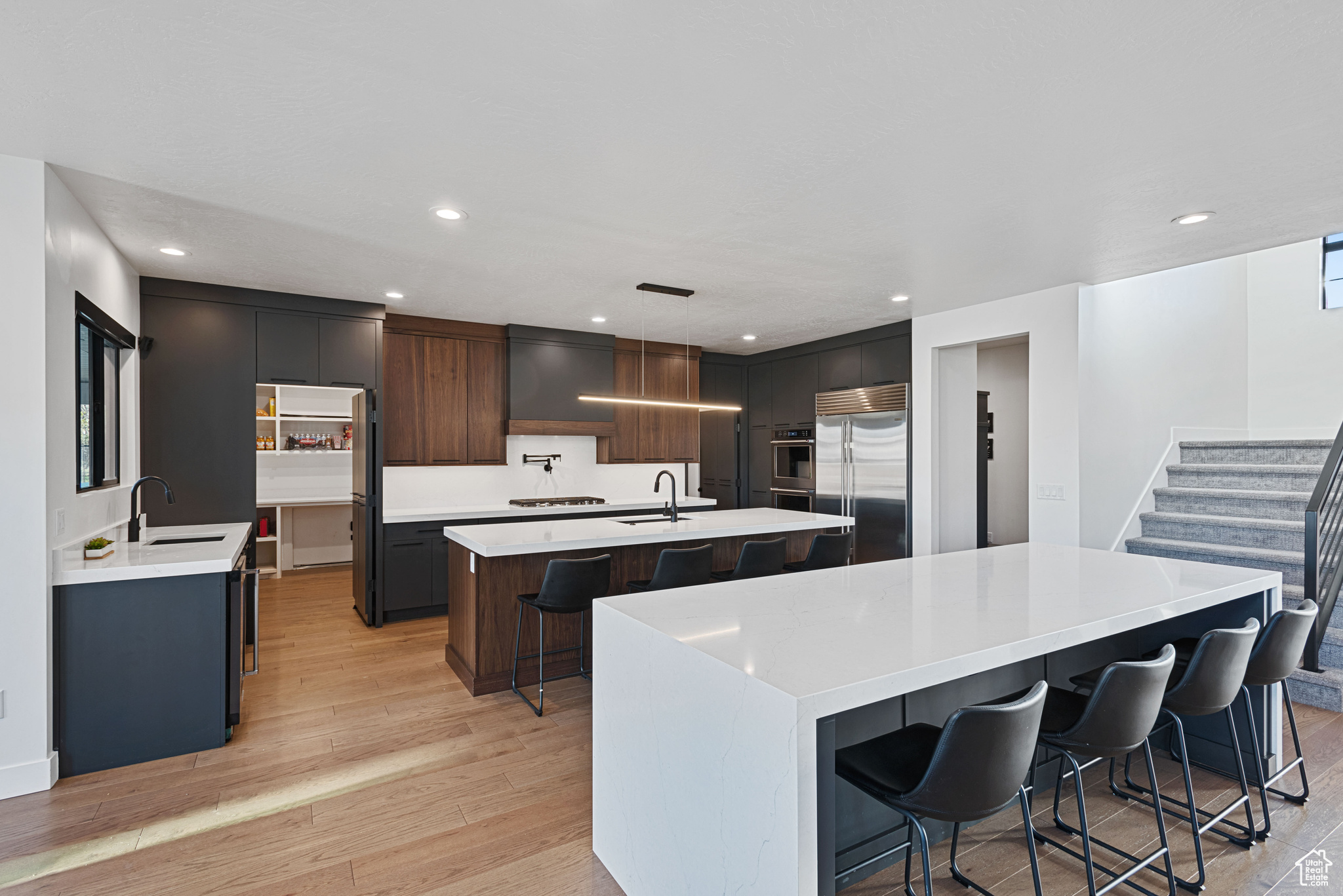 Kitchen with appliances with stainless steel finishes, a center island with sink, hanging light fixtures, and a kitchen breakfast bar