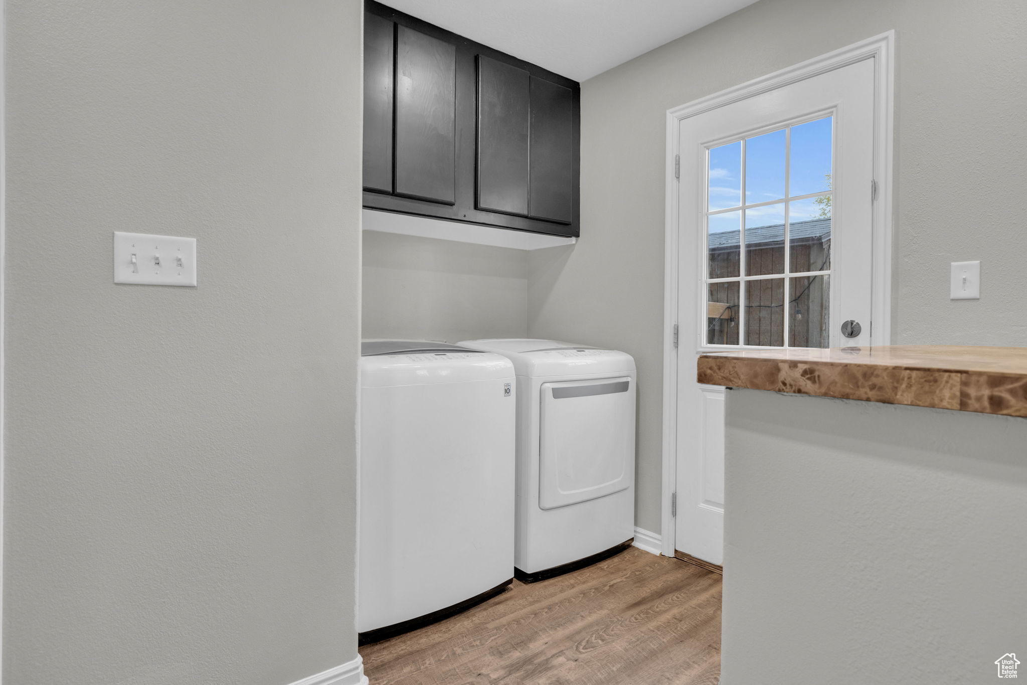 Laundry area with washer and dryer, light hardwood / wood-style floors, and cabinets