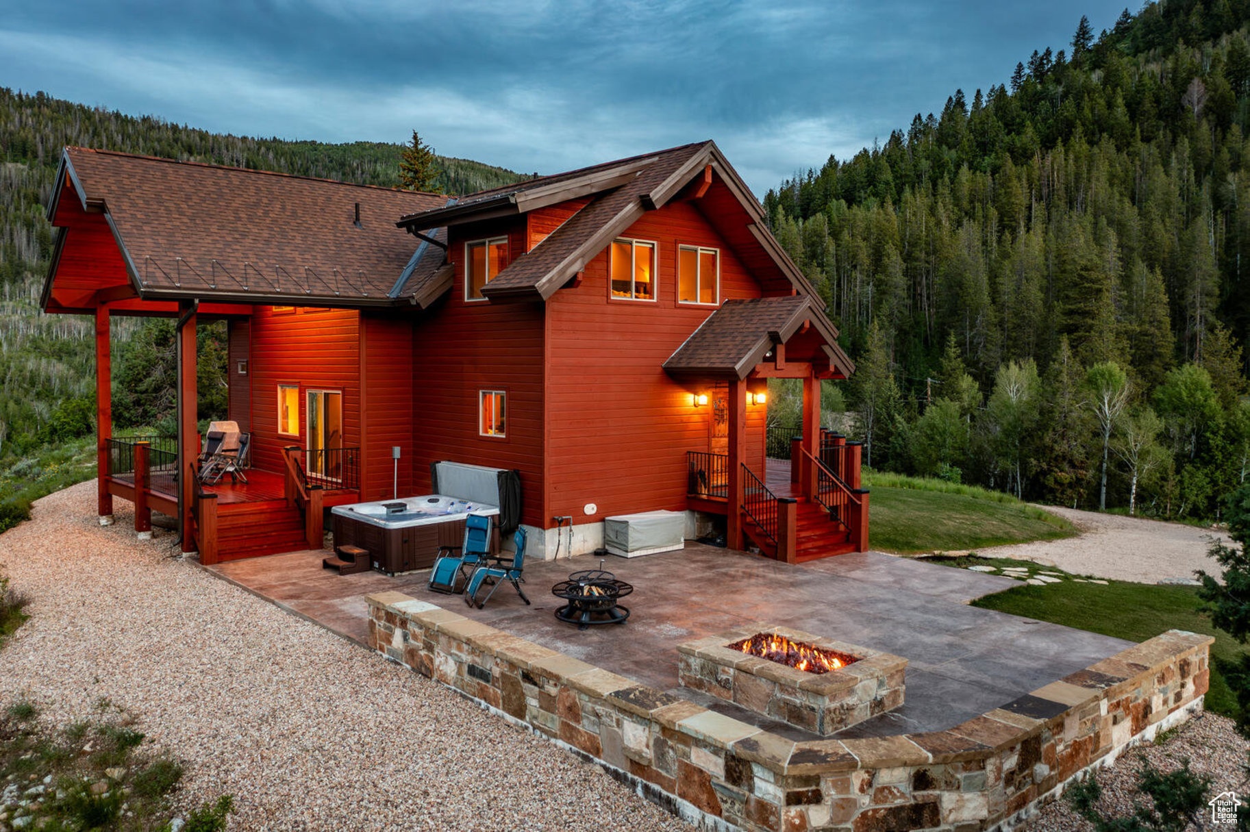 Rear view of property with a lawn, a wooden deck, a patio area, an outdoor fire pit, and a hot tub