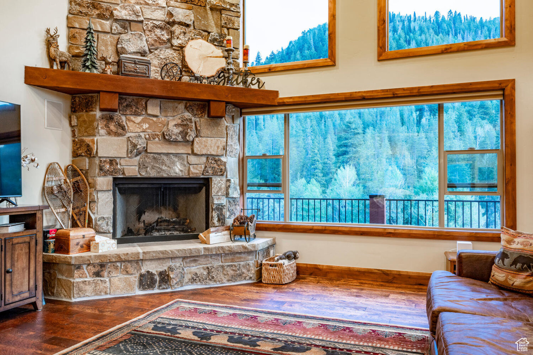 Living room featuring a stone fireplace, wood-type flooring, and a wealth of natural light