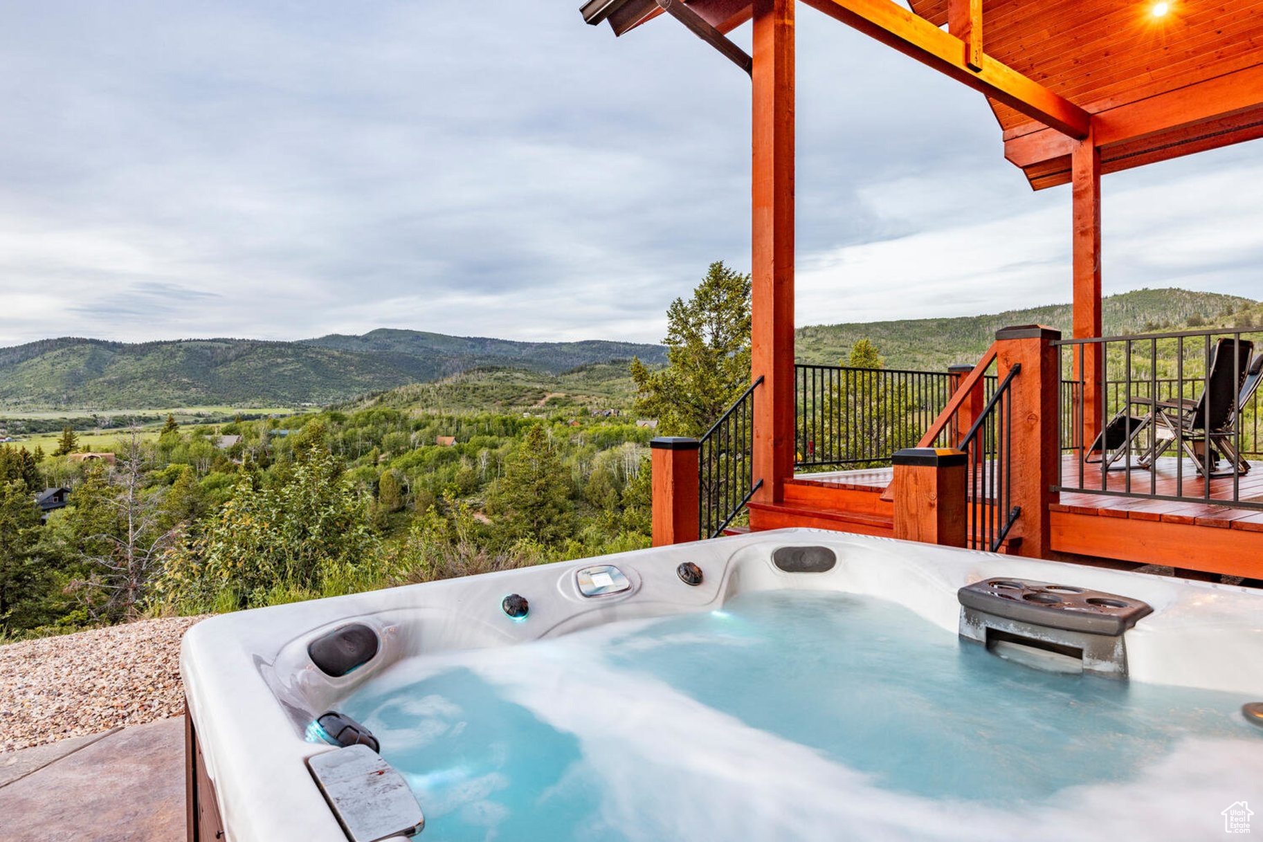 View of patio with a deck with mountain view and a hot tub