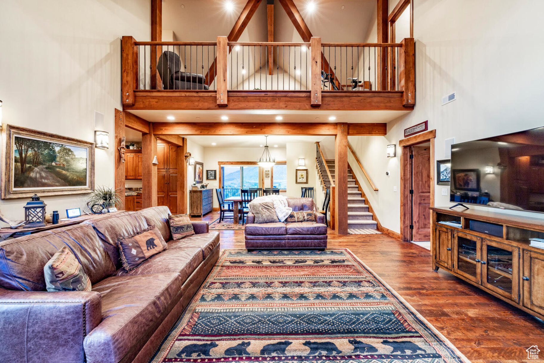 Living room with wood-type flooring, a towering ceiling, and a chandelier