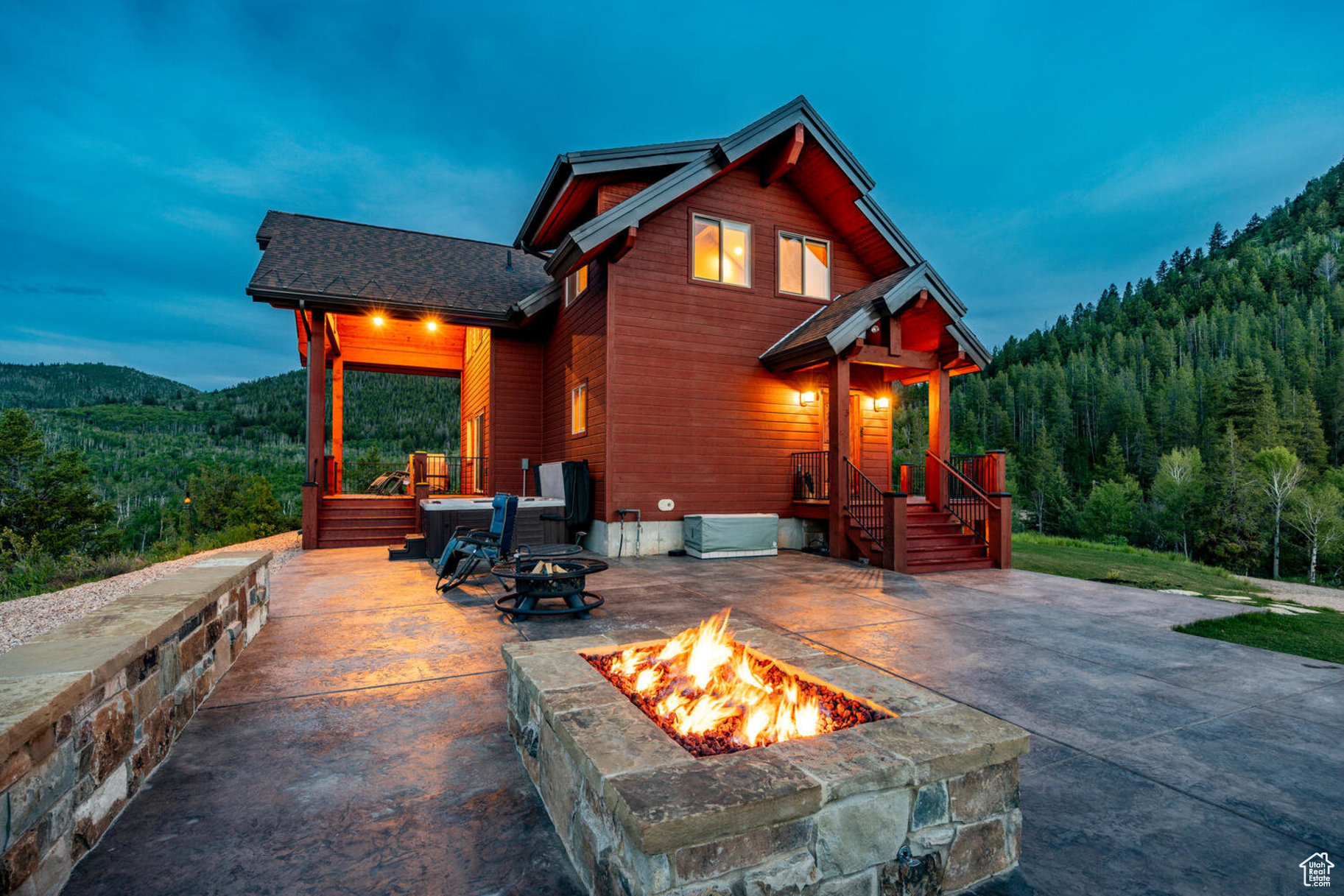 Back house at dusk with a mountain view, a patio, and a fire pit