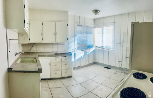 Kitchen featuring decorative backsplash, refrigerator, plenty of natural light, and light tile patterned flooring