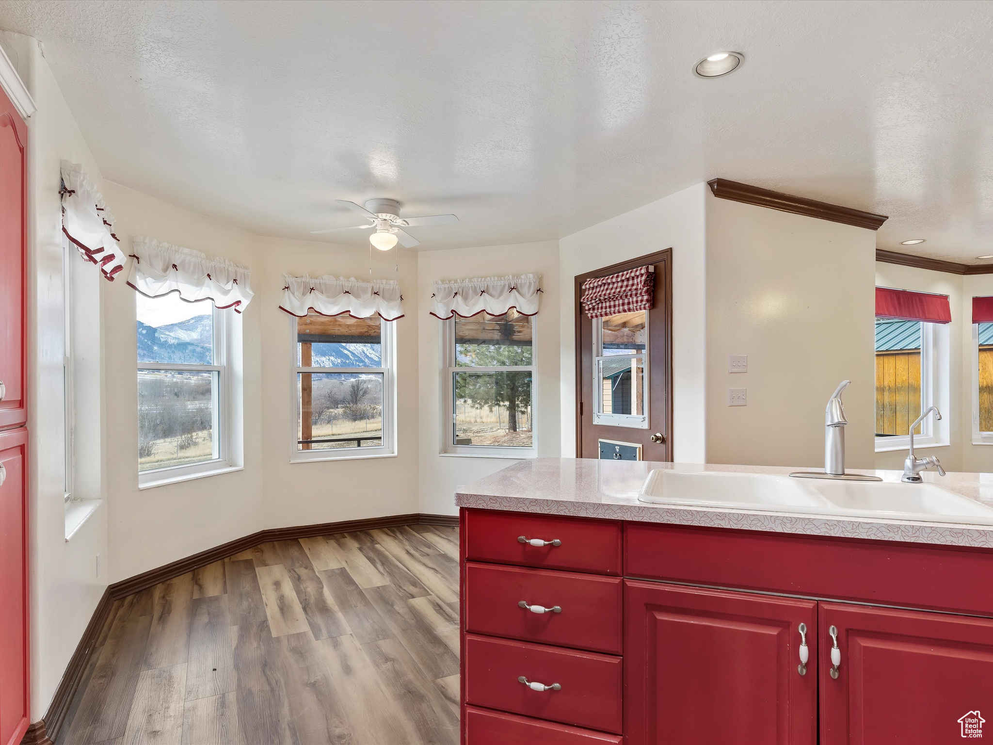 Kitchen featuring ornamental molding, a textured ceiling, ceiling fan, sink, and light hardwood / wood-style floors