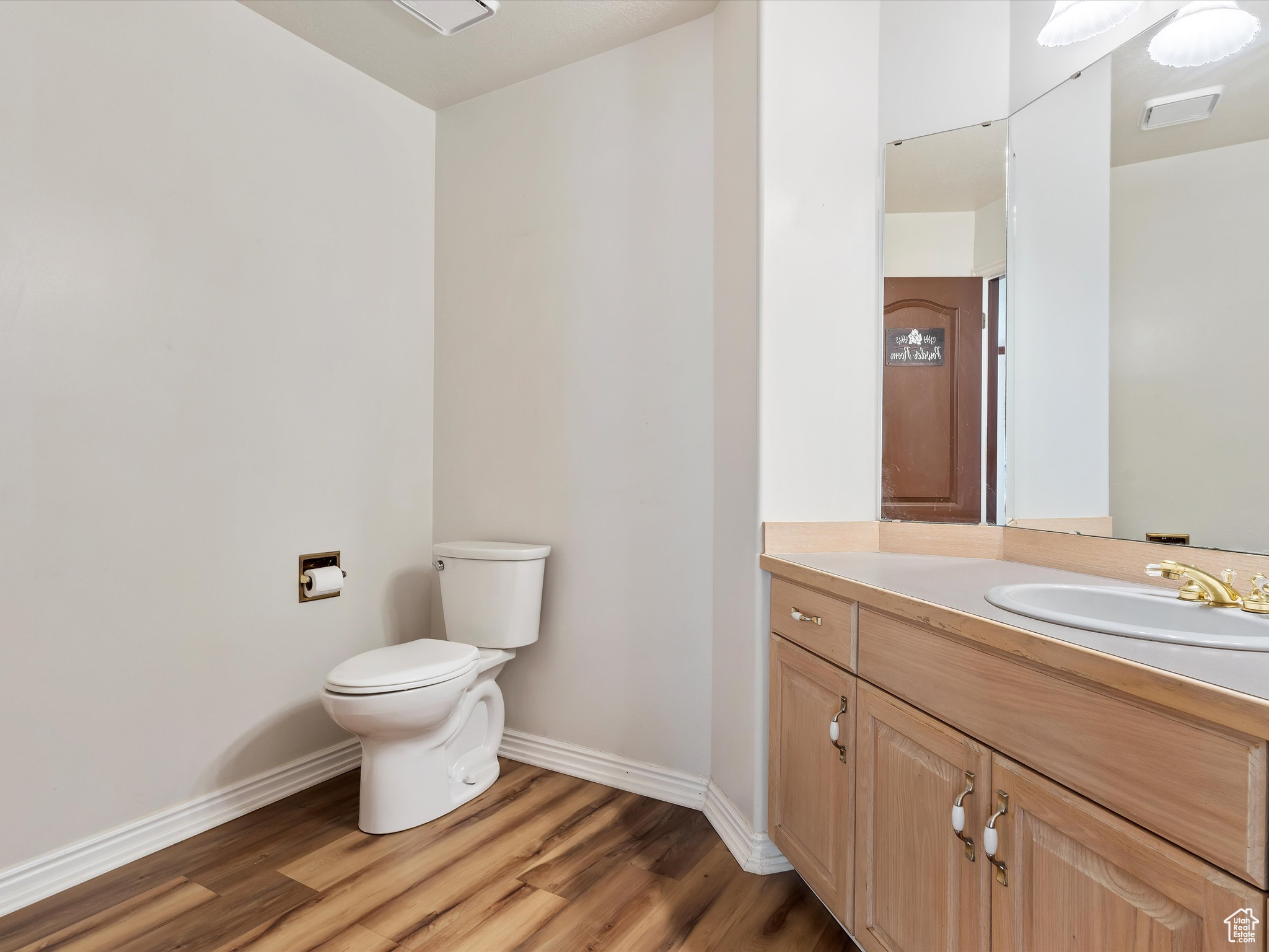 Bathroom featuring hardwood / wood-style flooring, vanity, and toilet