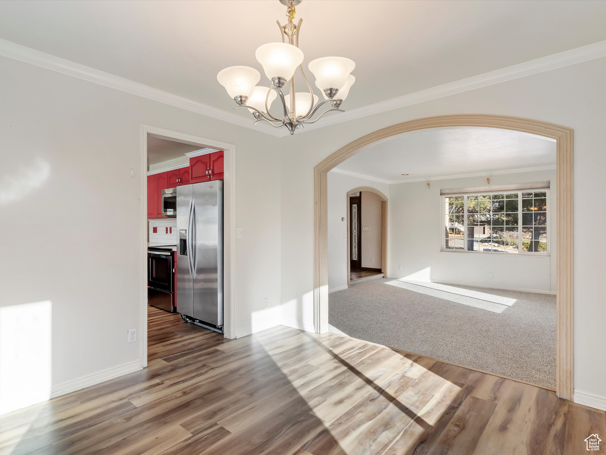 Interior space with crown molding, a notable chandelier, and hardwood / wood-style flooring