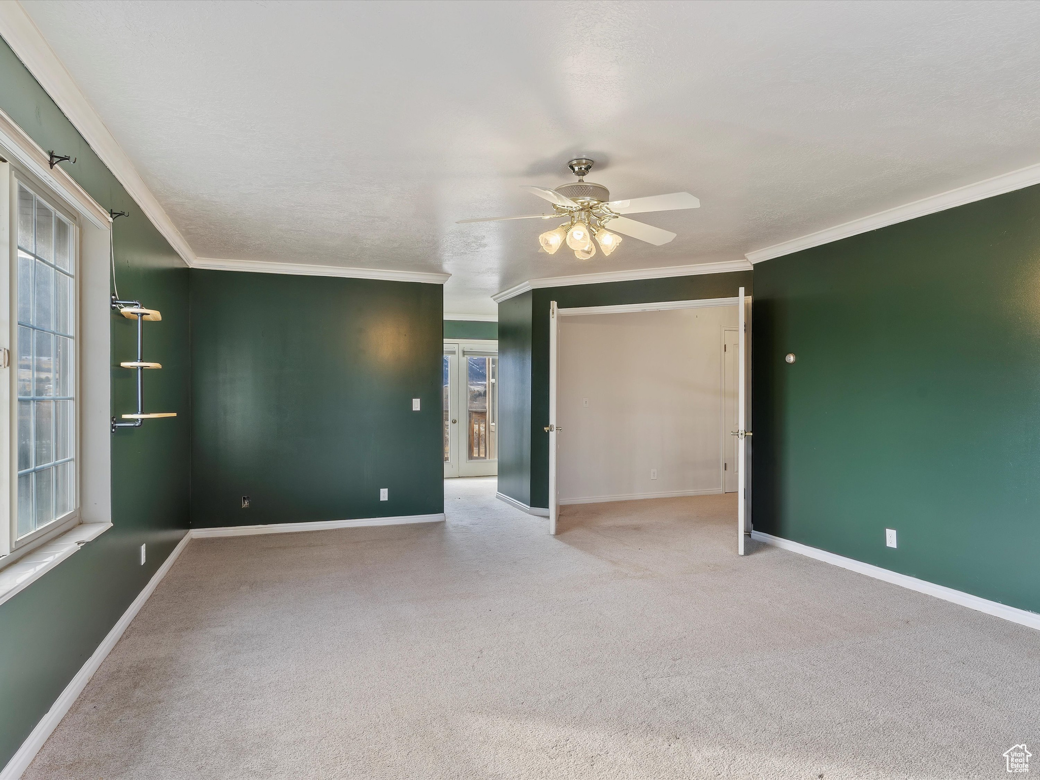 Carpeted spare room with ceiling fan and crown molding