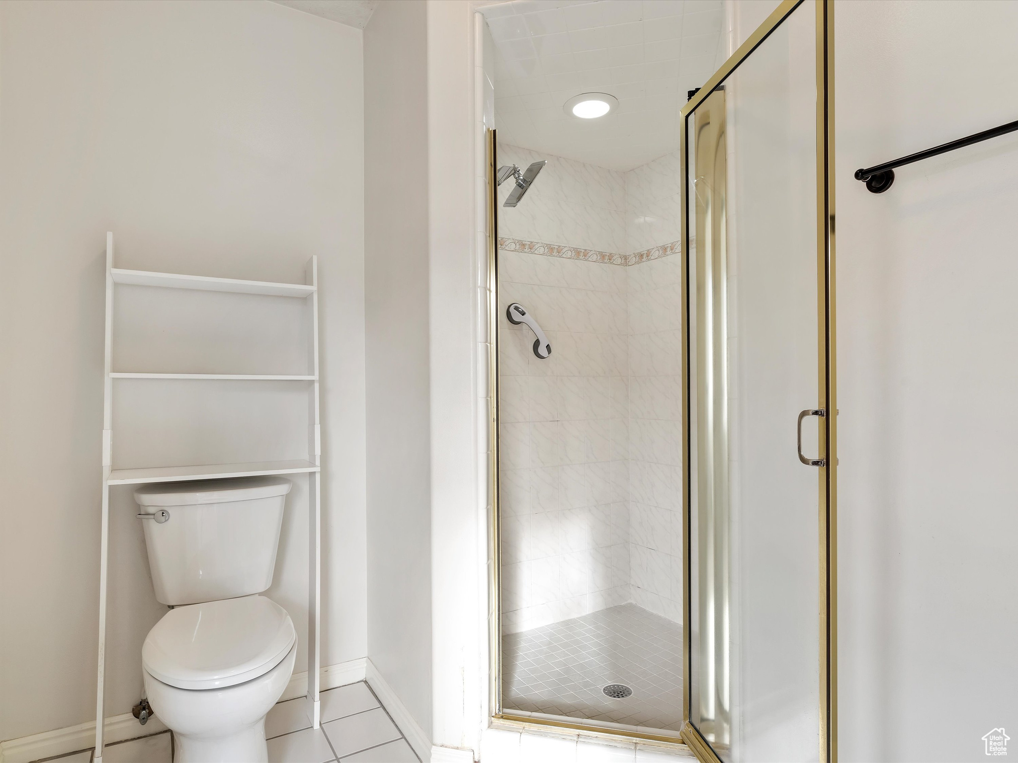 Bathroom featuring tile patterned floors, an enclosed shower, and toilet