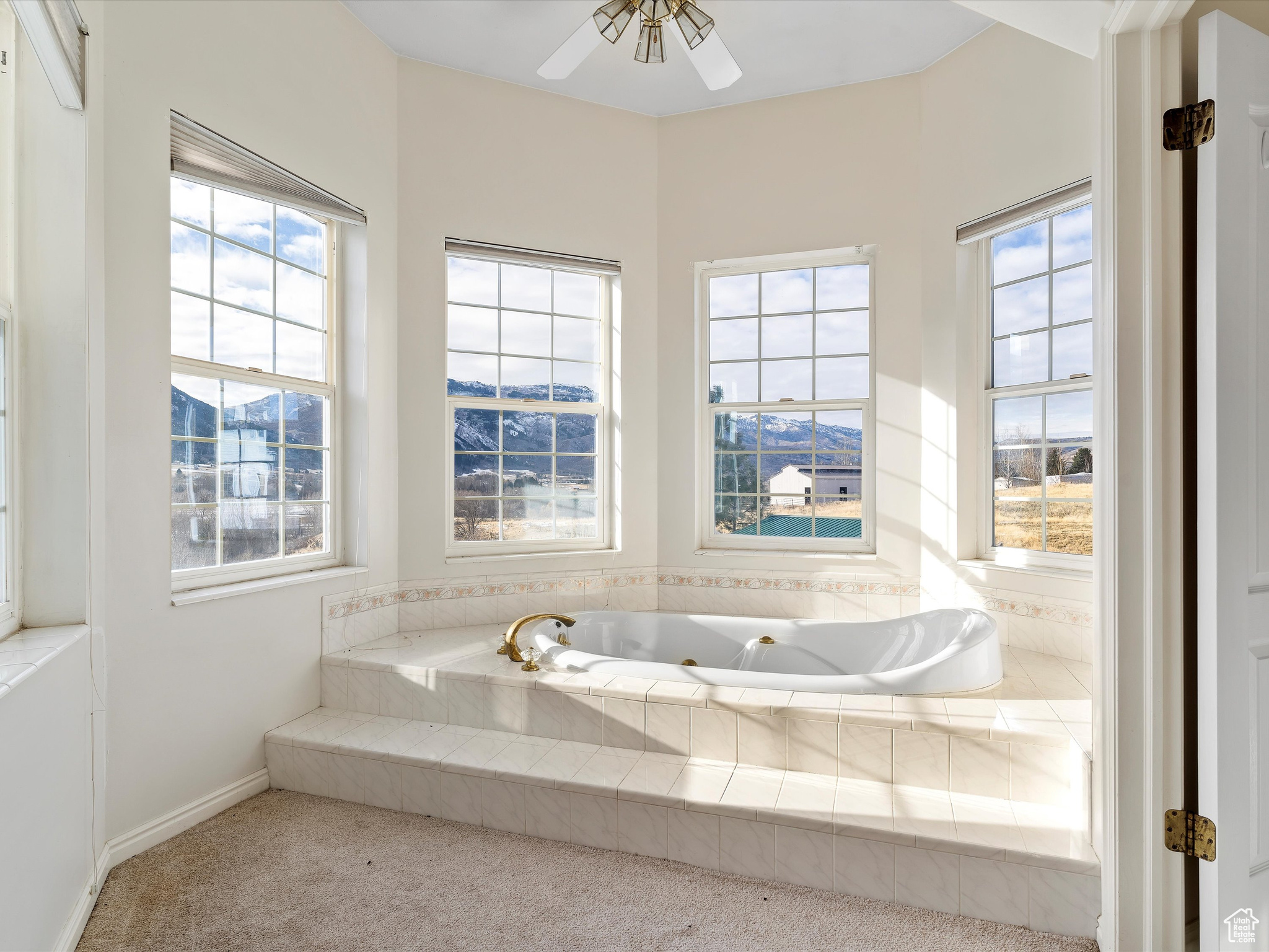 Bathroom with a wealth of natural light, ceiling fan, and a relaxing tiled tub