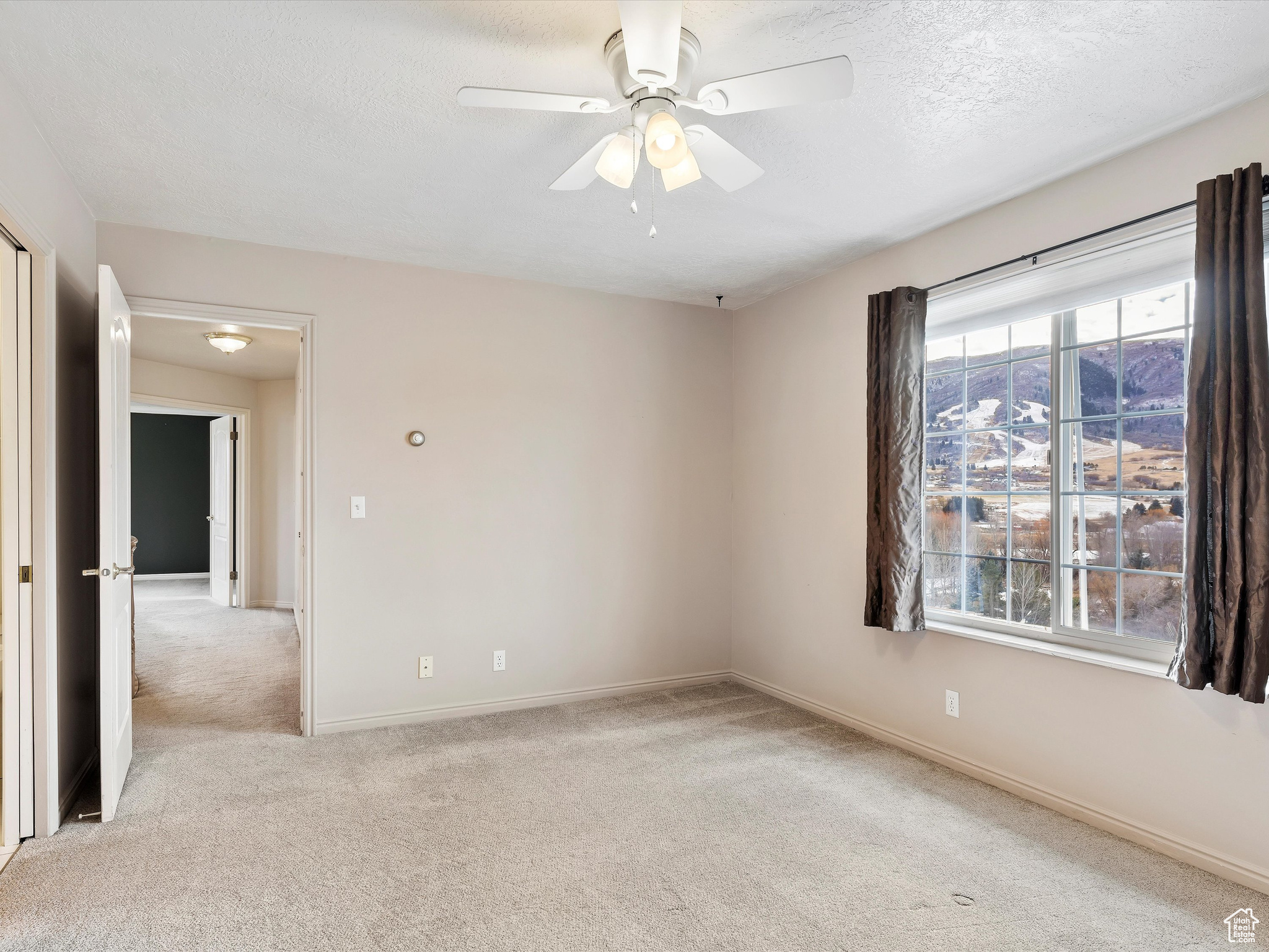 Spare room featuring light carpet, a textured ceiling, and ceiling fan