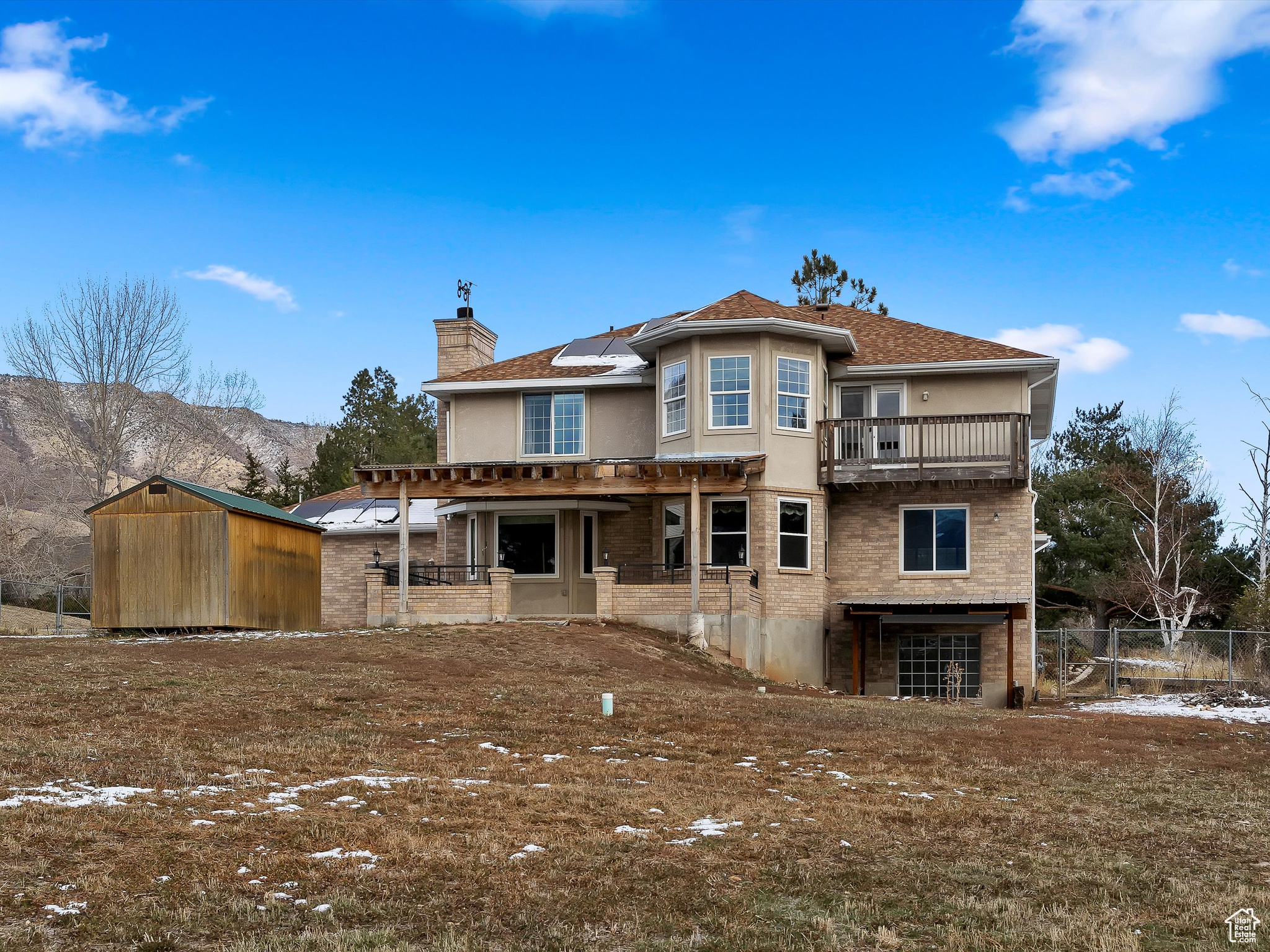 Rear view of property featuring a mountain view, a balcony, and solar panels