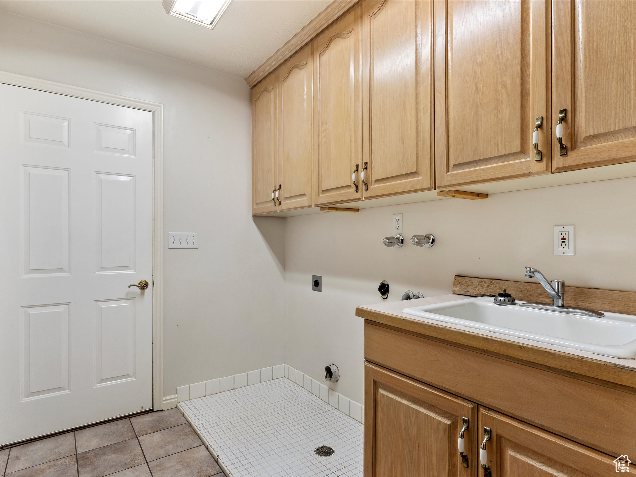 Laundry area with cabinets, light tile patterned flooring, hookup for an electric dryer, and sink