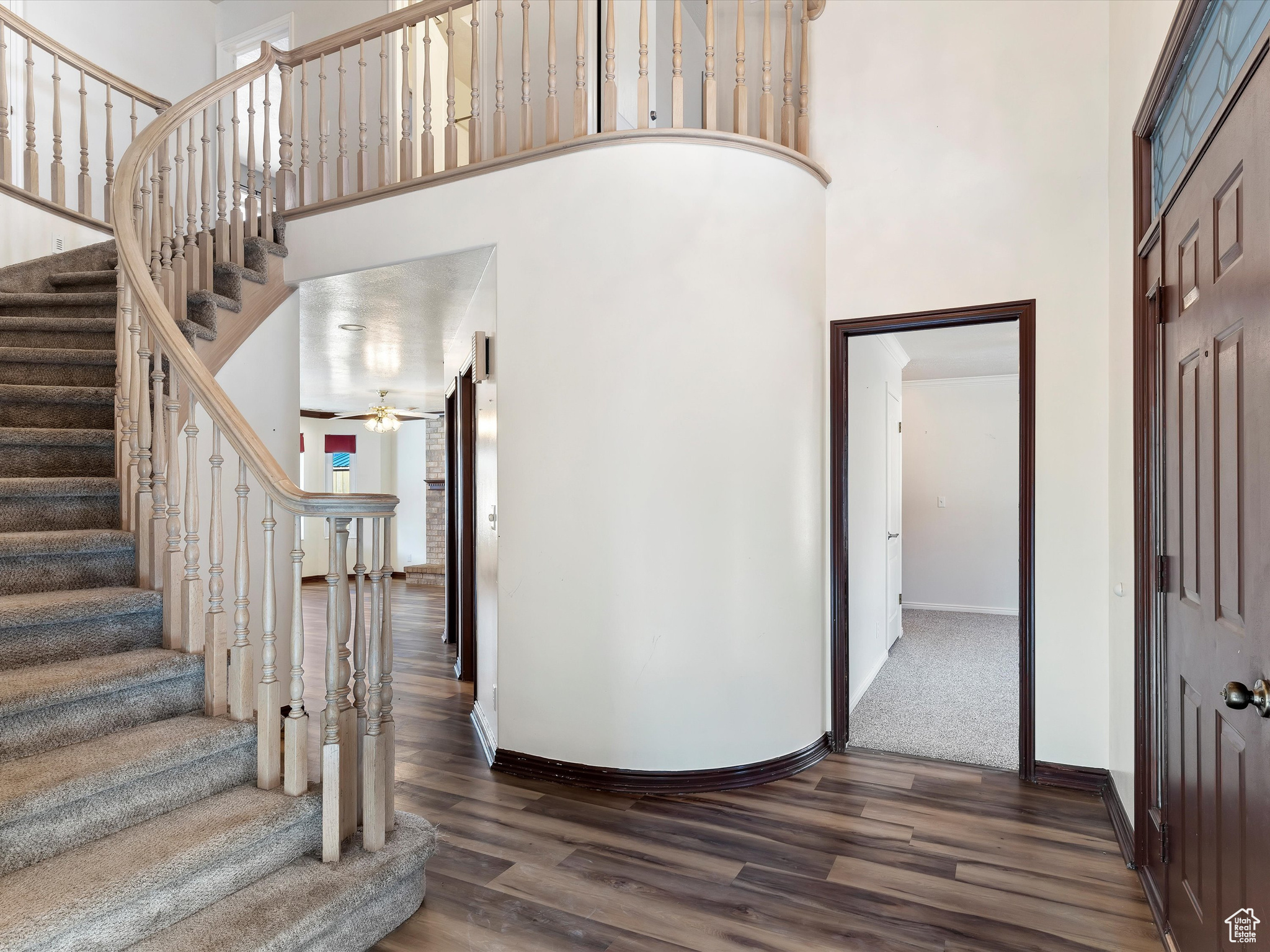 Foyer entrance with ceiling fan, dark hardwood / wood-style floors, and a towering ceiling