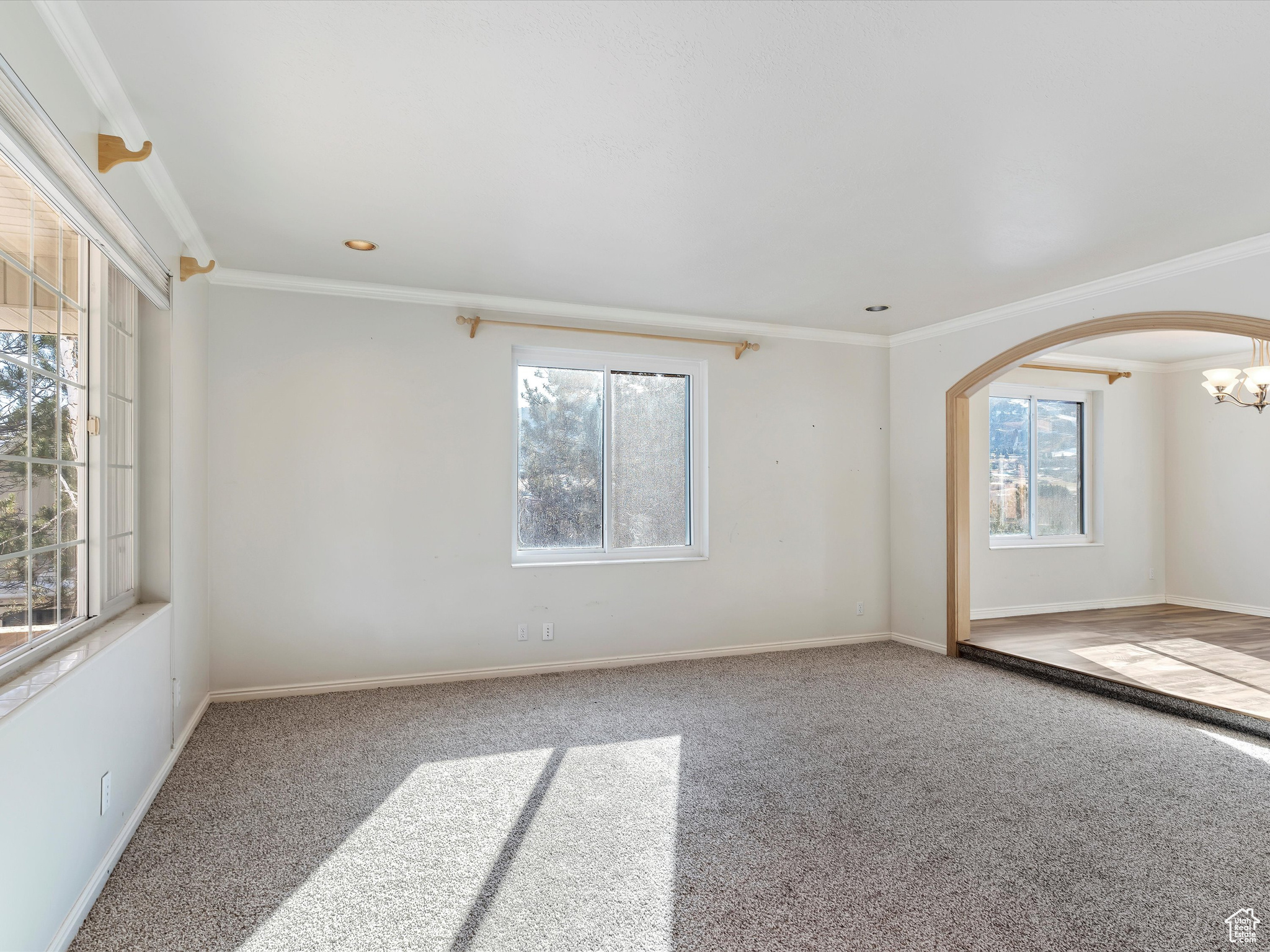 Empty room with carpet flooring, ornamental molding, and an inviting chandelier