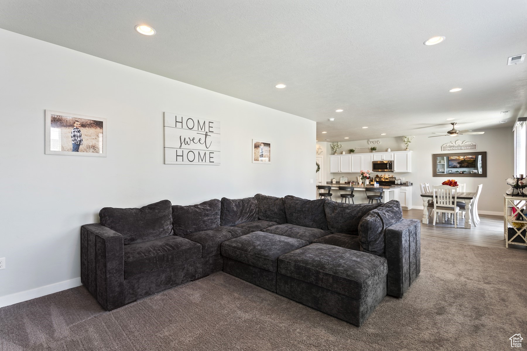 Living room with ceiling fan and dark carpet