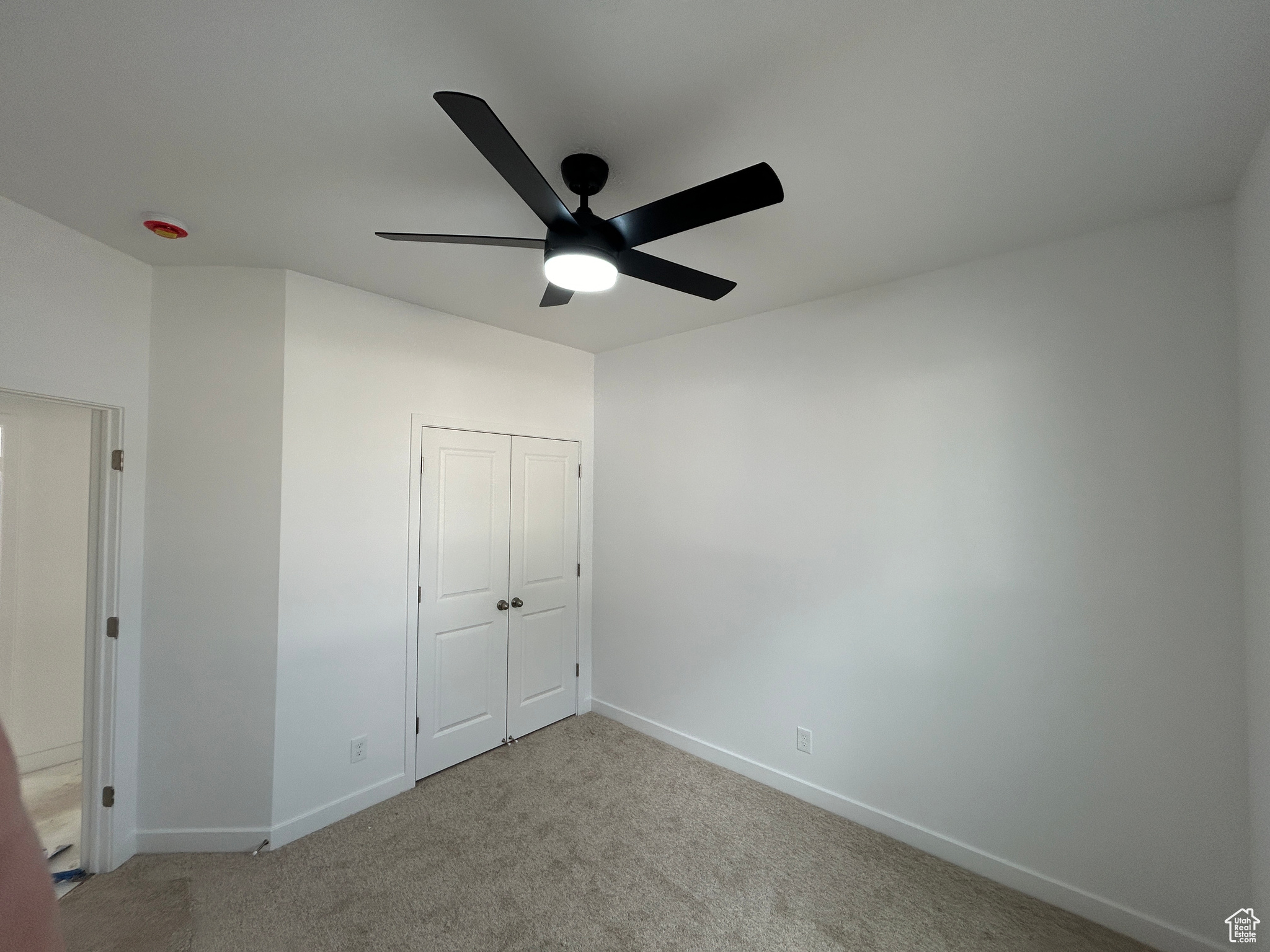 Unfurnished bedroom with ceiling fan, light colored carpet, and a closet