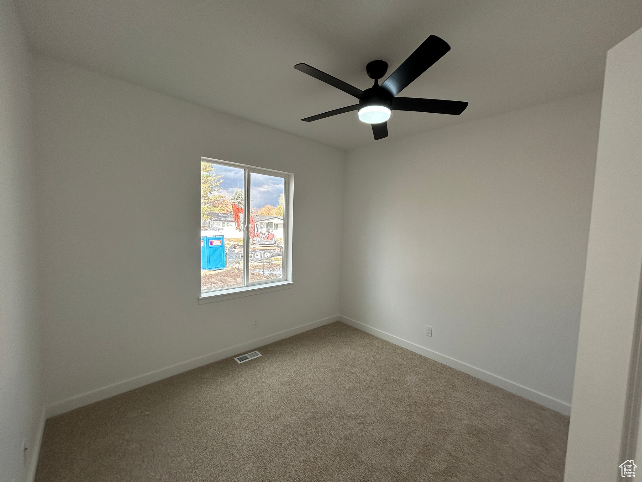 Carpeted empty room featuring ceiling fan